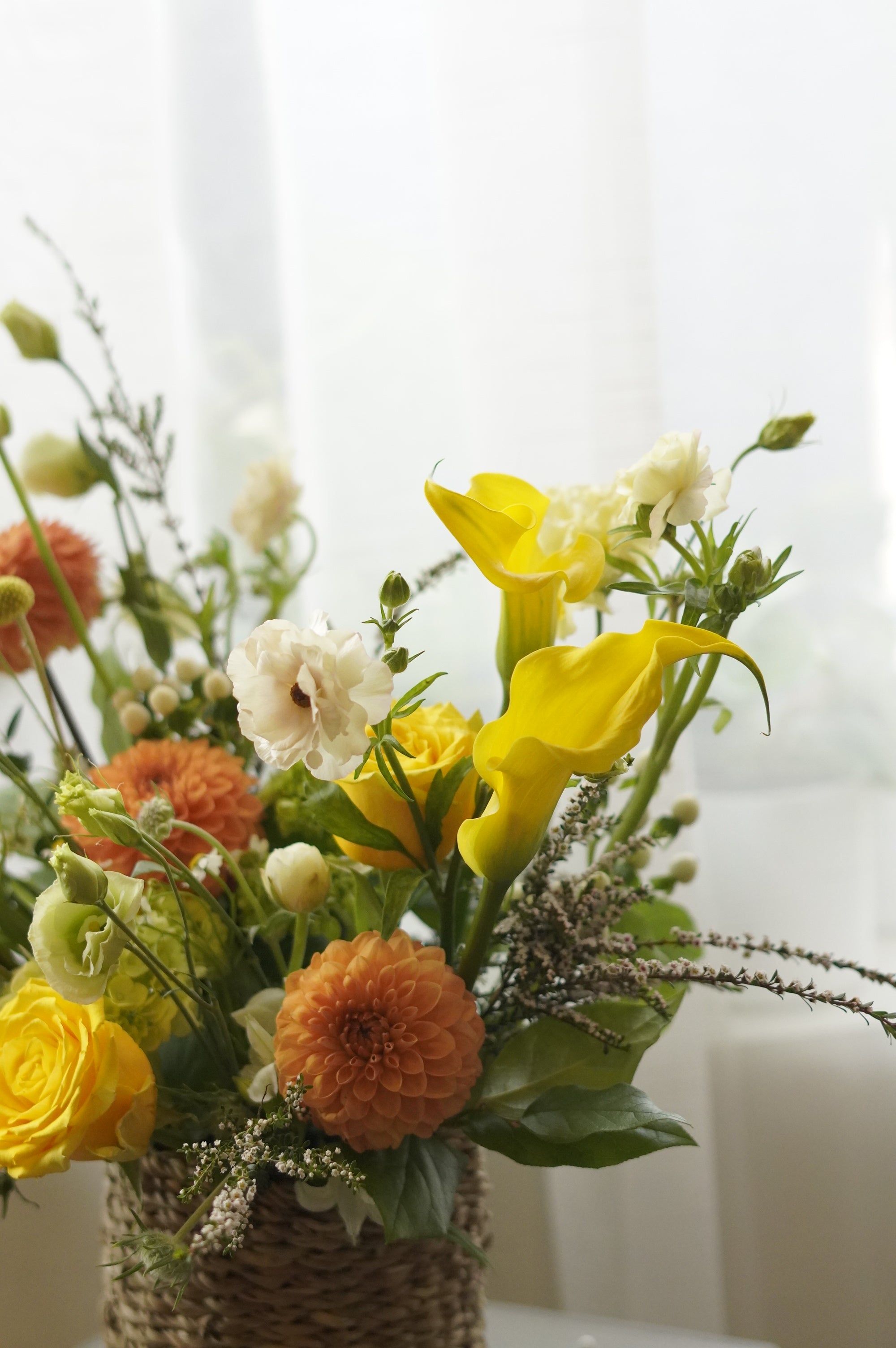 Yellow and orange seasonal flower basket with roses and garden flowers