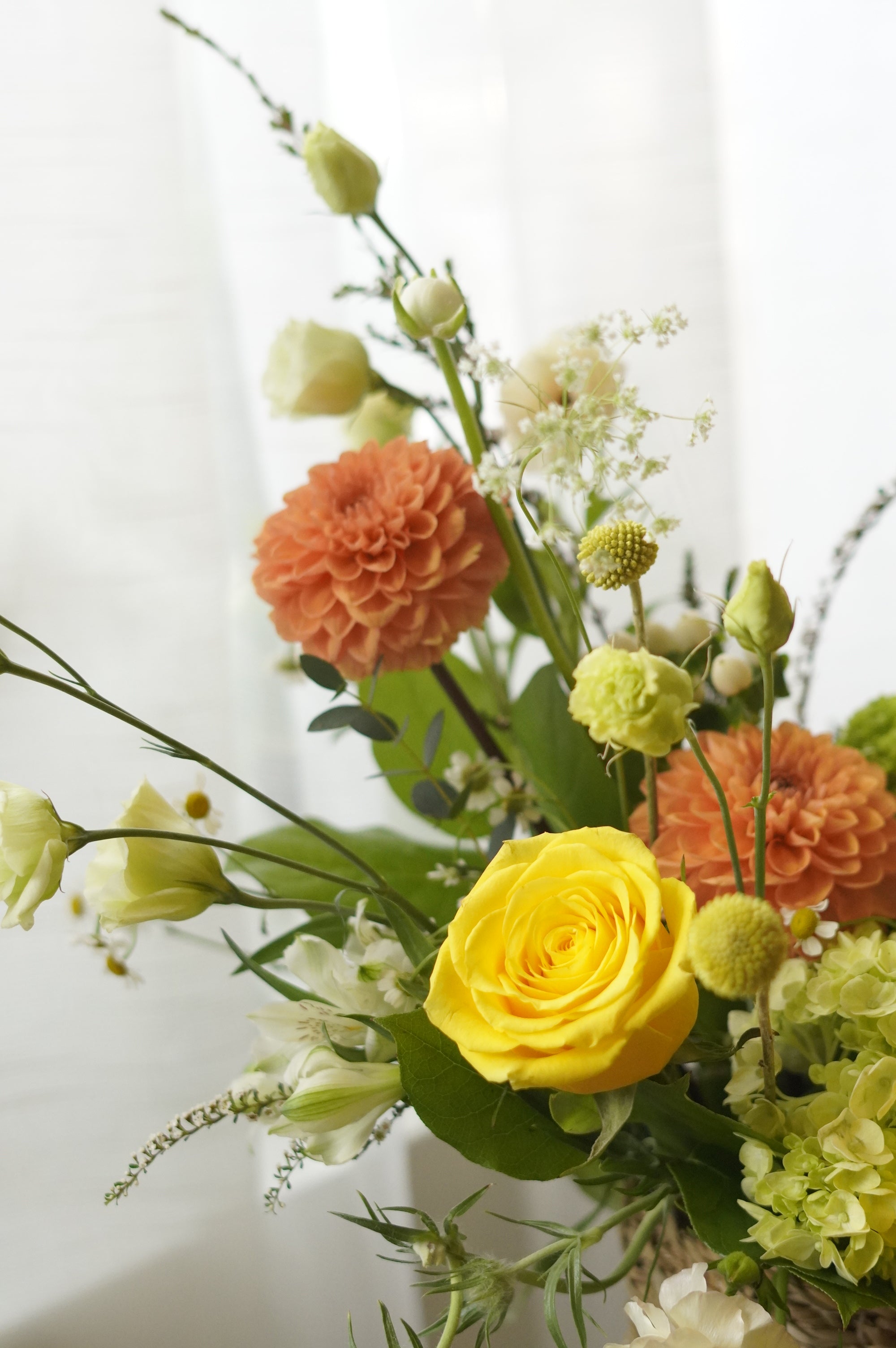 Yellow and orange seasonal flower basket with roses and garden flowers