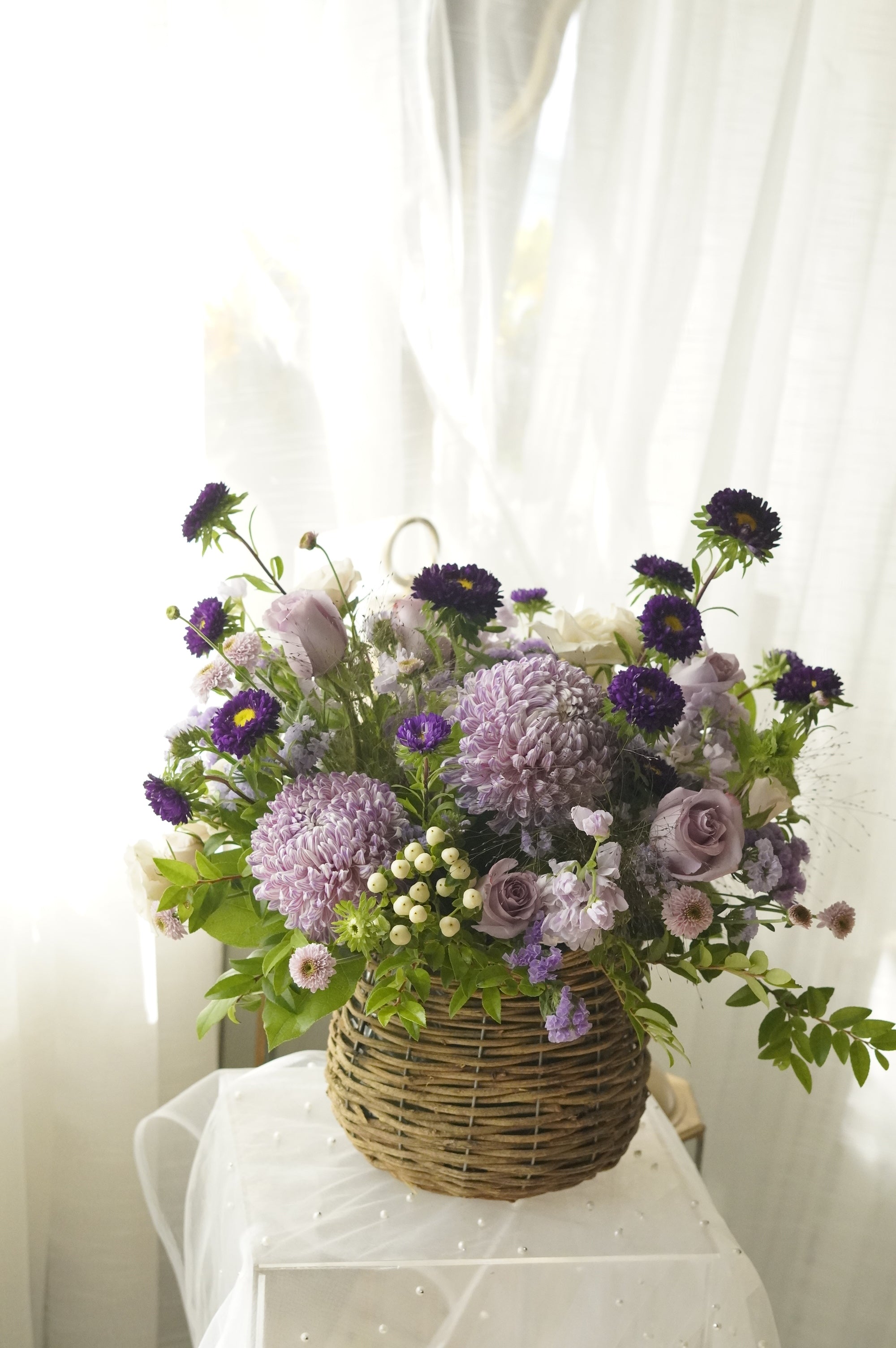 Close detail of hand-woven basket base with trailing greenery and stock florals