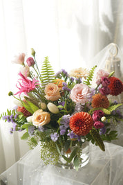 Orange, peach and lavender seasonal flower arrangement with textured greenery