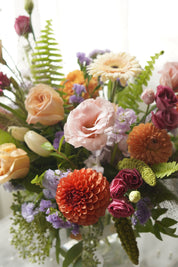 Close-up of orange dahlias, pink lisianthus and purple seasonal flowers in Tangerine arrangement