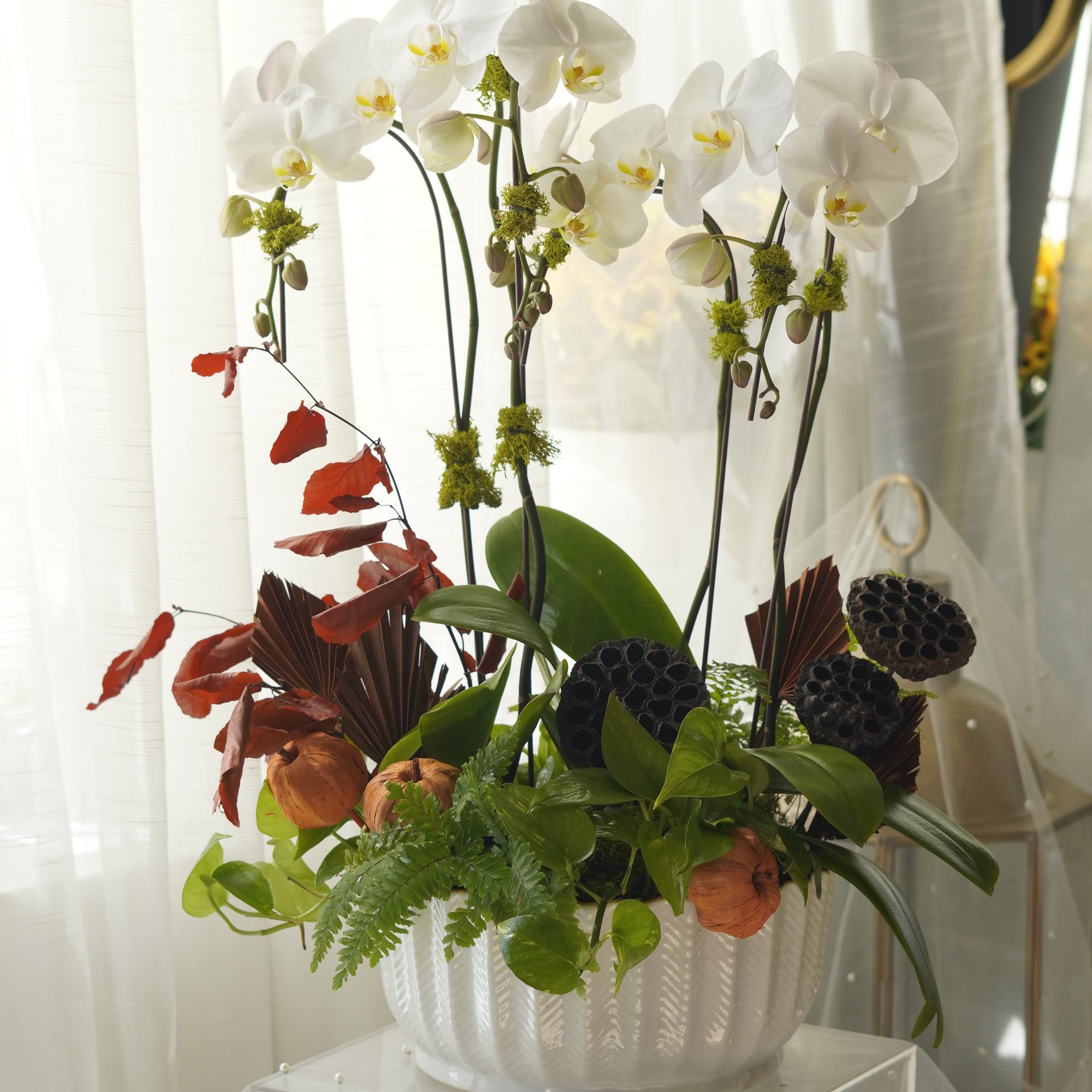Close-up of moss-wrapped orchid stems and pomegranate accents