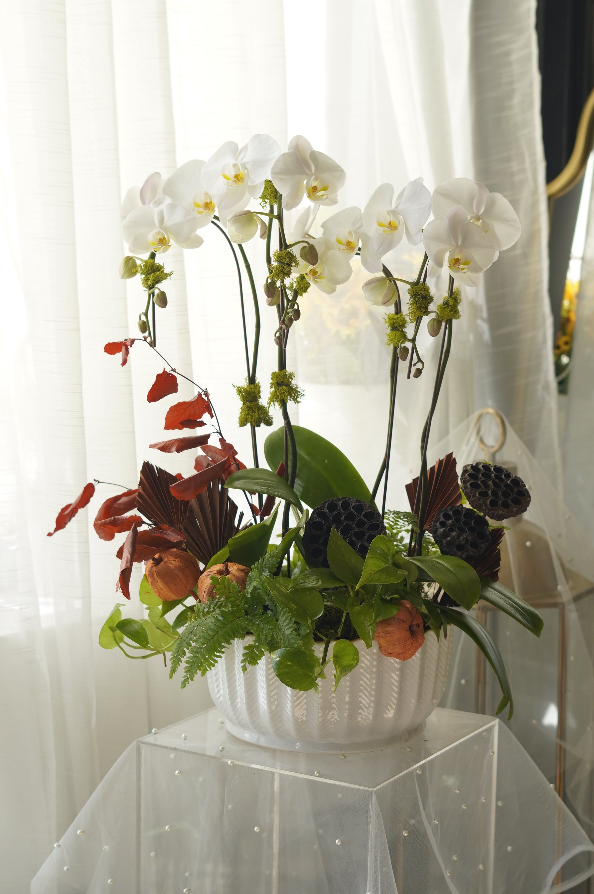 Close-up of moss-wrapped orchid stems and pomegranate accents