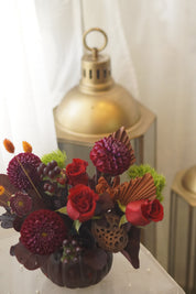 Red roses and burgundy dahlias with dried palm accents — autumn flower arrangement