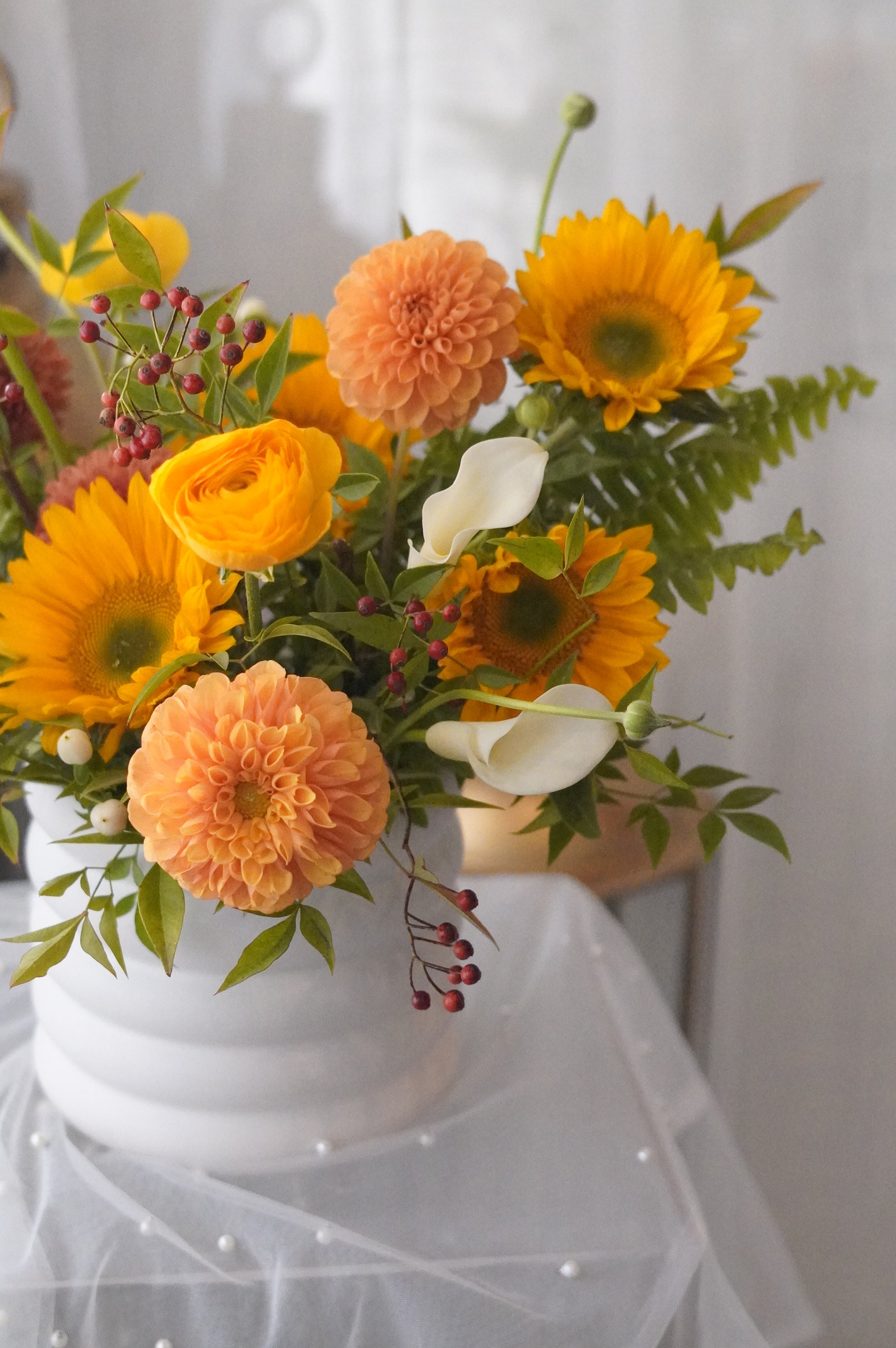 Peach dahlias, golden sunflowers, white calla lilies, and berry accents
