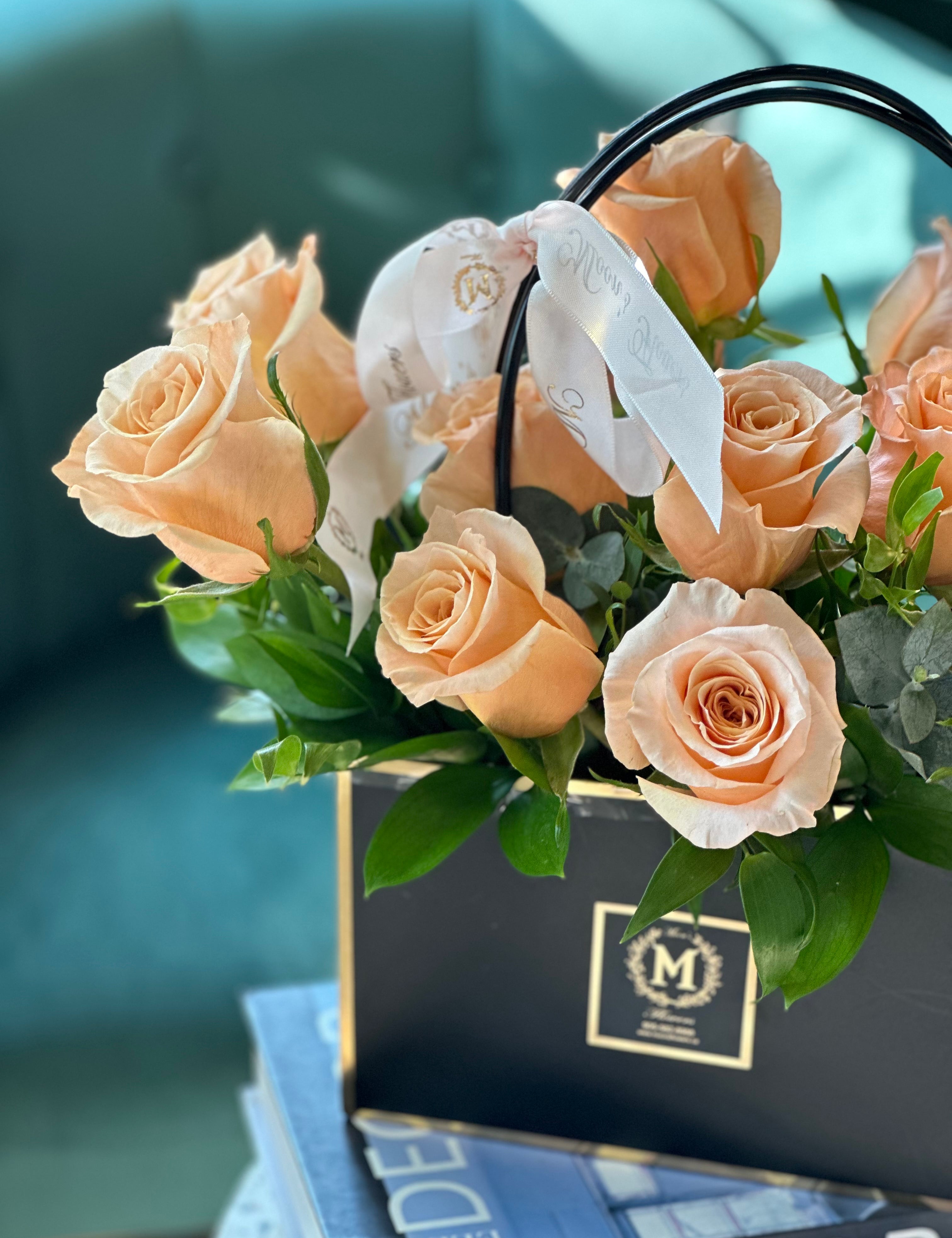 Close-up of peach roses and eucalyptus in the Dozen Peach Roses – Basket of Love arrangement