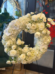 Elegant circular funeral tribute featuring premium white blooms and lush greenery, handcrafted by Moon's Flowers Toronto