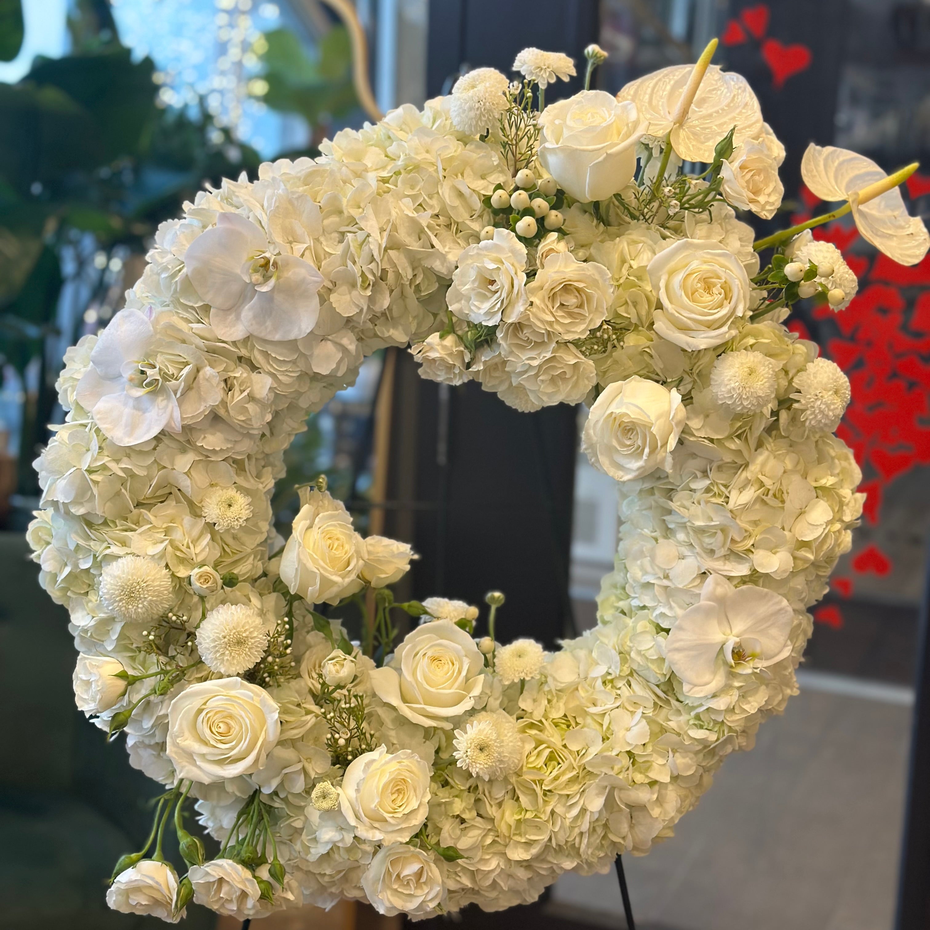 Elegant circular funeral tribute featuring premium white blooms and lush greenery, handcrafted by Moon's Flowers Toronto