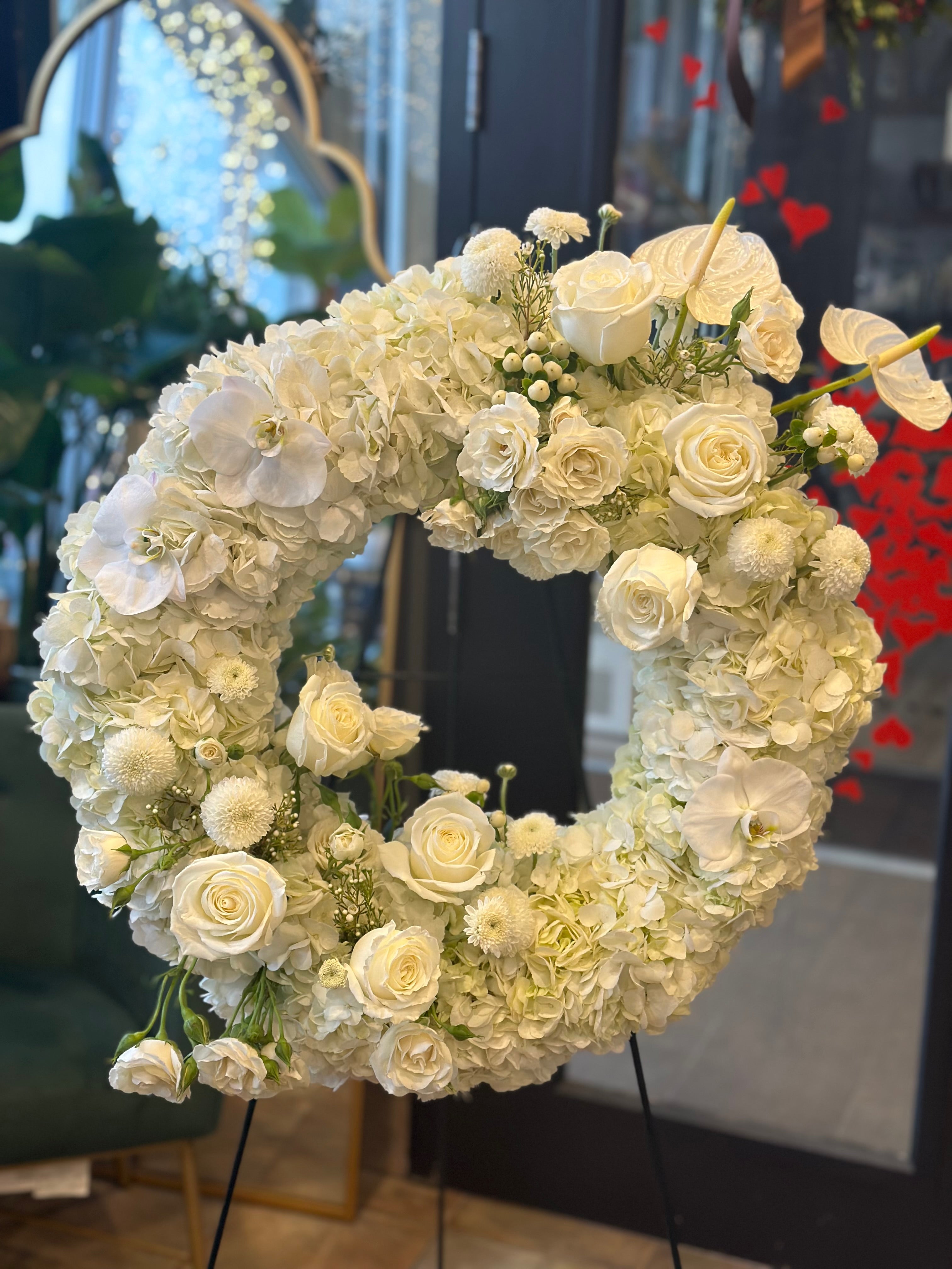 Elegant circular funeral tribute featuring premium white blooms and lush greenery, handcrafted by Moon's Flowers Toronto