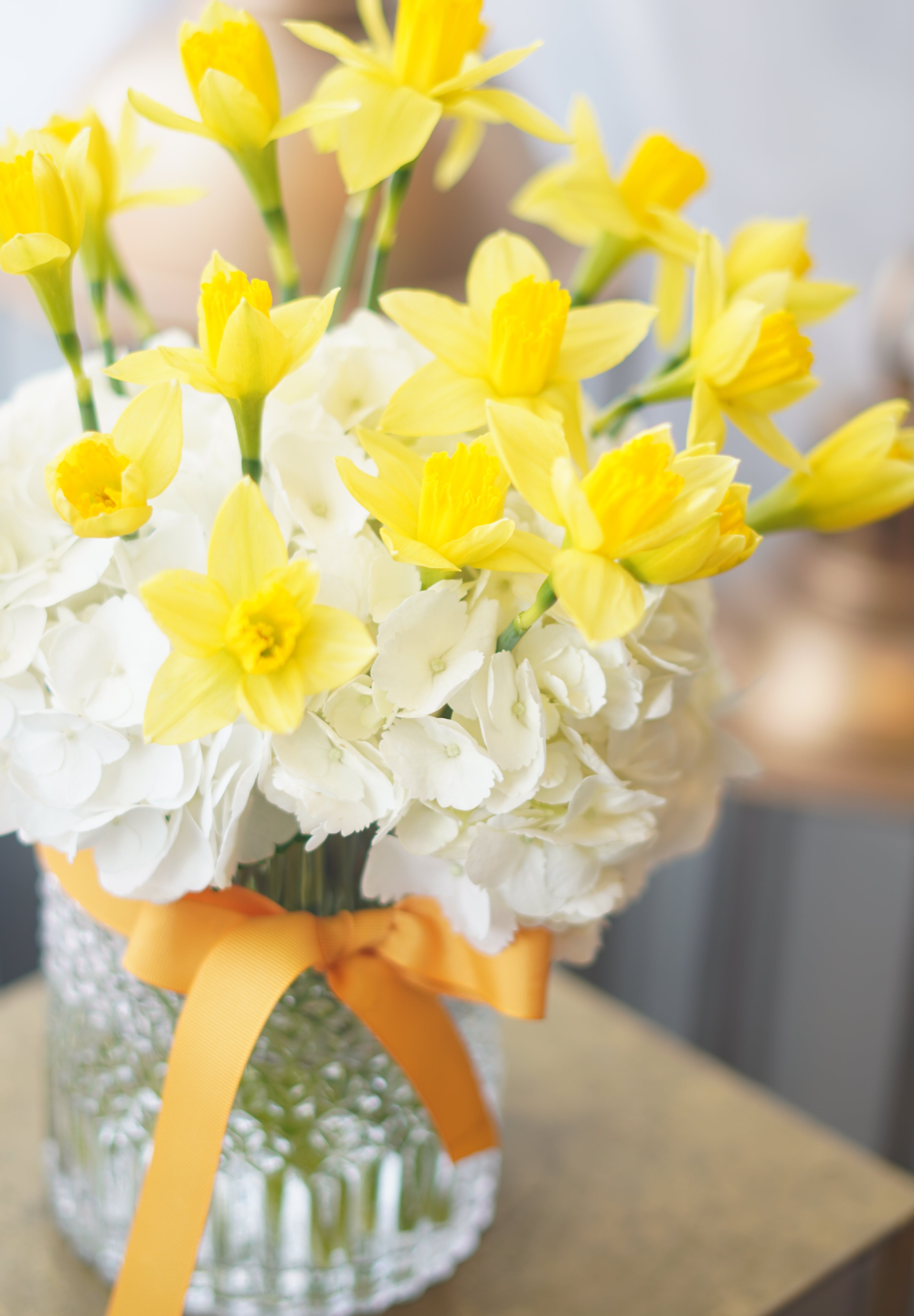 Elegant daffodil arrangement in clear glass vase with natural greenery
