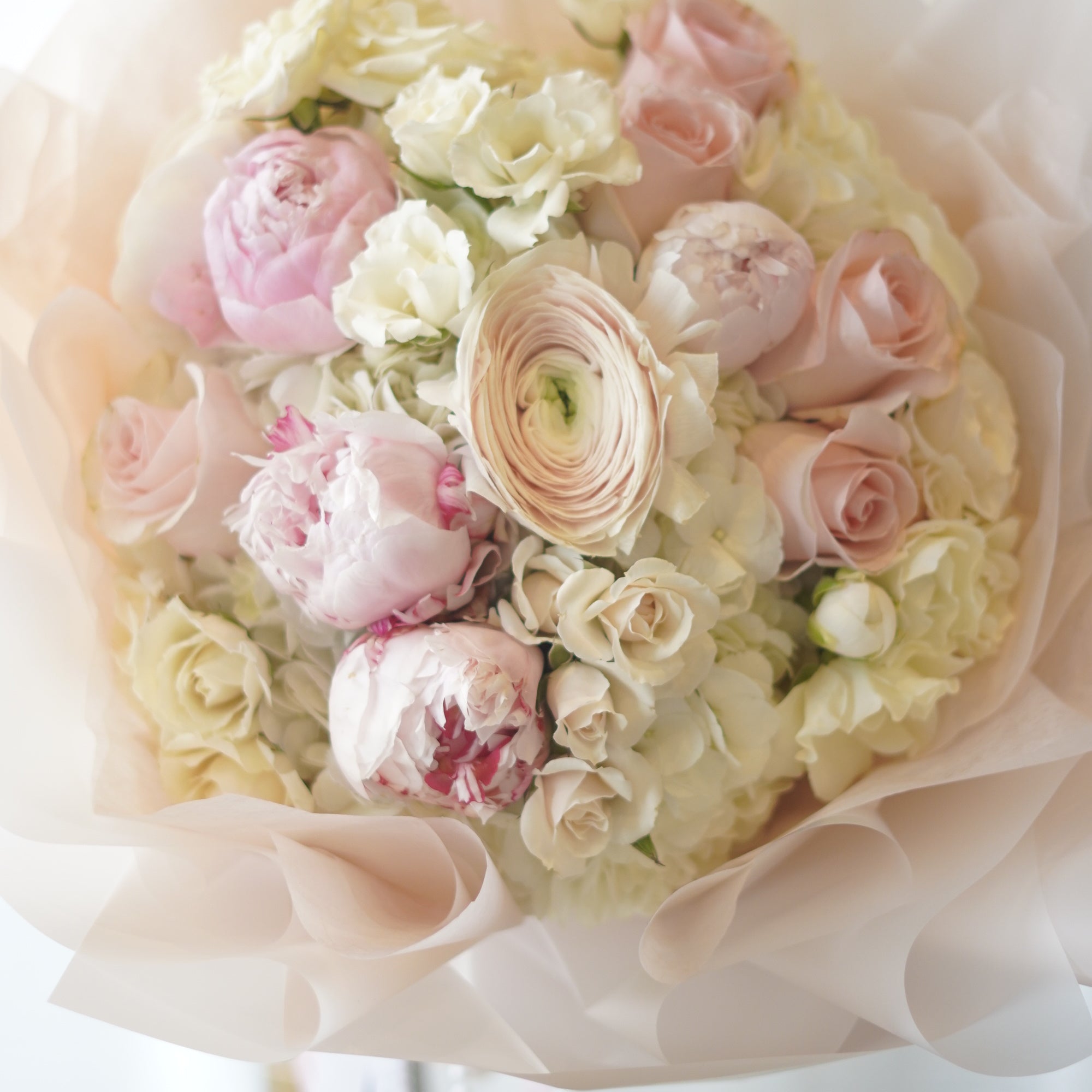 Elegant pink and ivory peony bouquet wrapped in soft blush paper