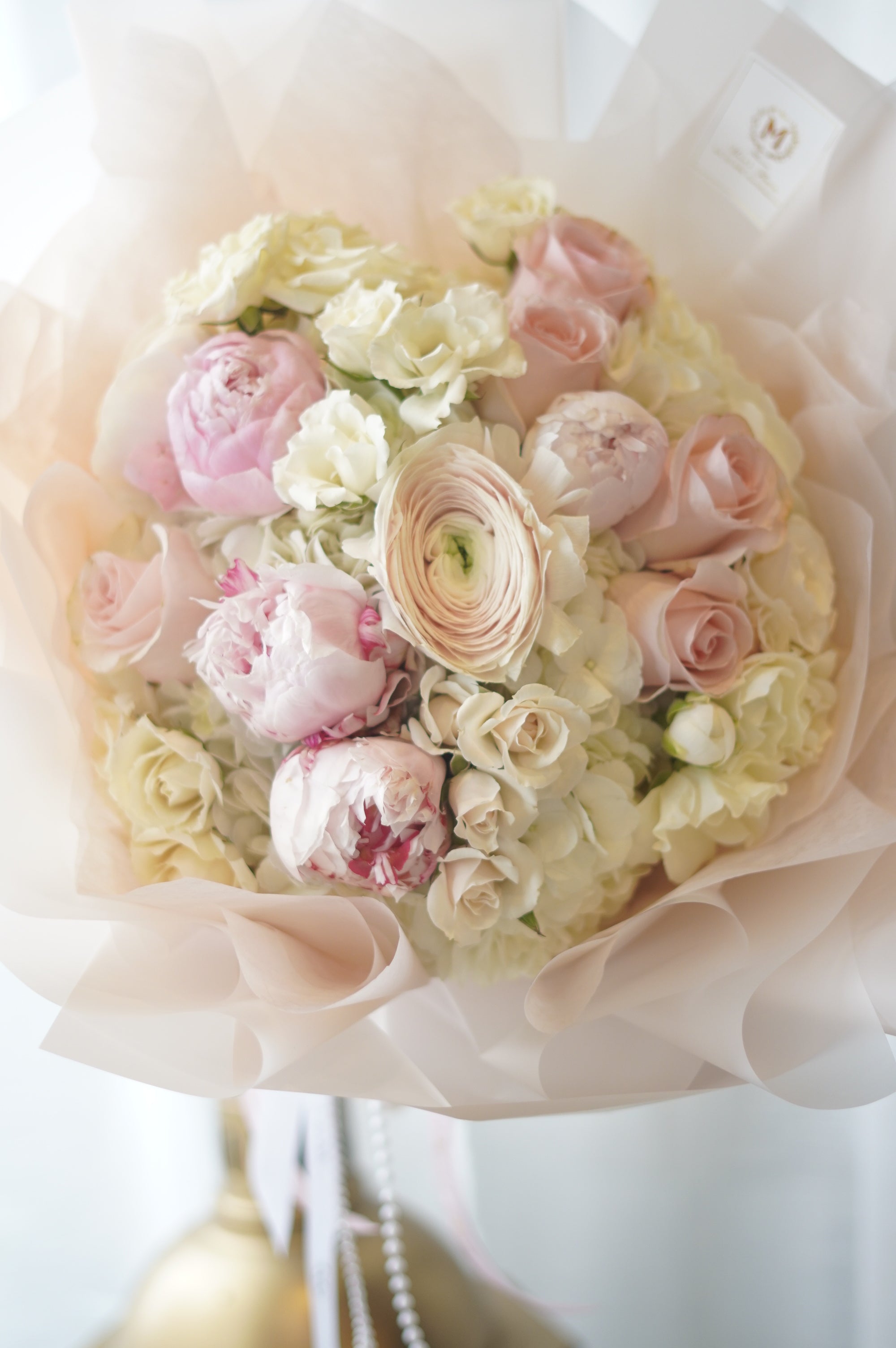 Elegant pink and ivory peony bouquet wrapped in soft blush paper