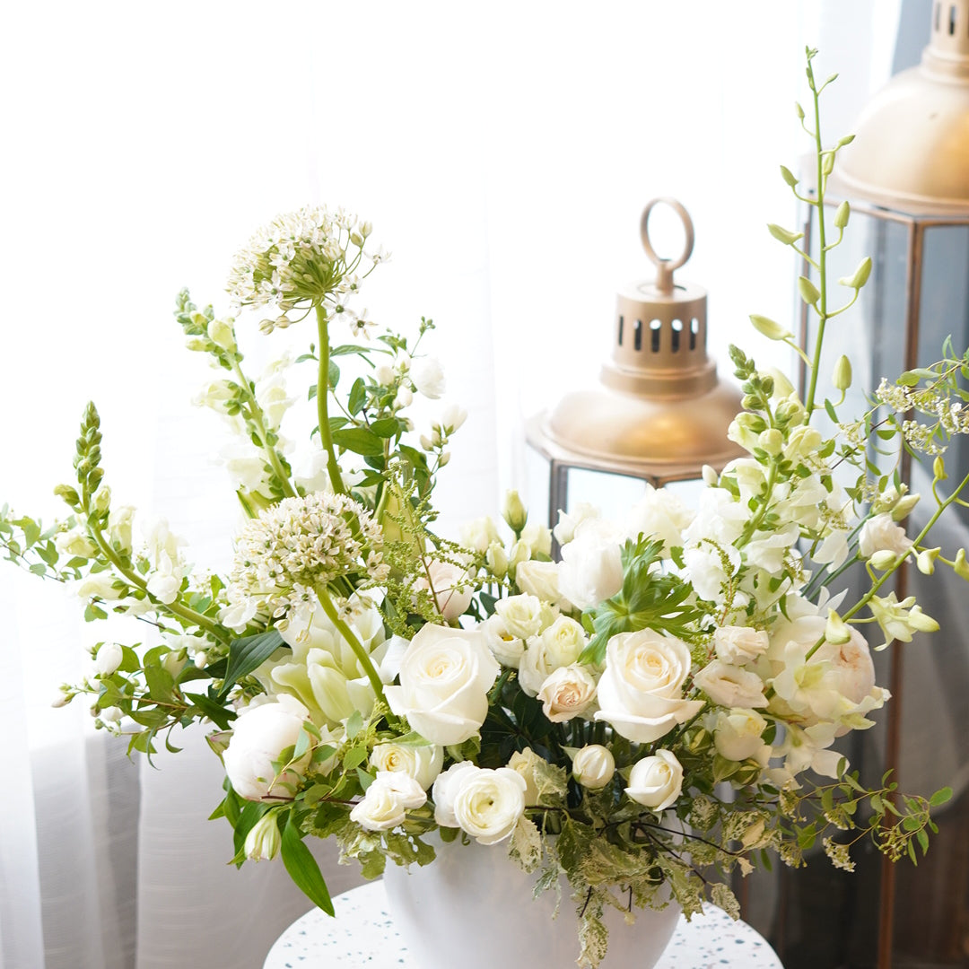 Elegant white condolence flower arrangement in a ceramic vase for funeral services in Toronto