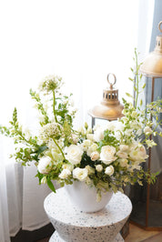 Elegant white condolence flower arrangement in a ceramic vase for funeral services in Toronto