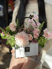 Flower arrangement in a gift bag: pink chrysanthemum, blush pink roses, pink gerbera daisy, green hydrangea. Luxury florist near me, offering flower delivery to Toronto and Oakville, On Moon's Flowers