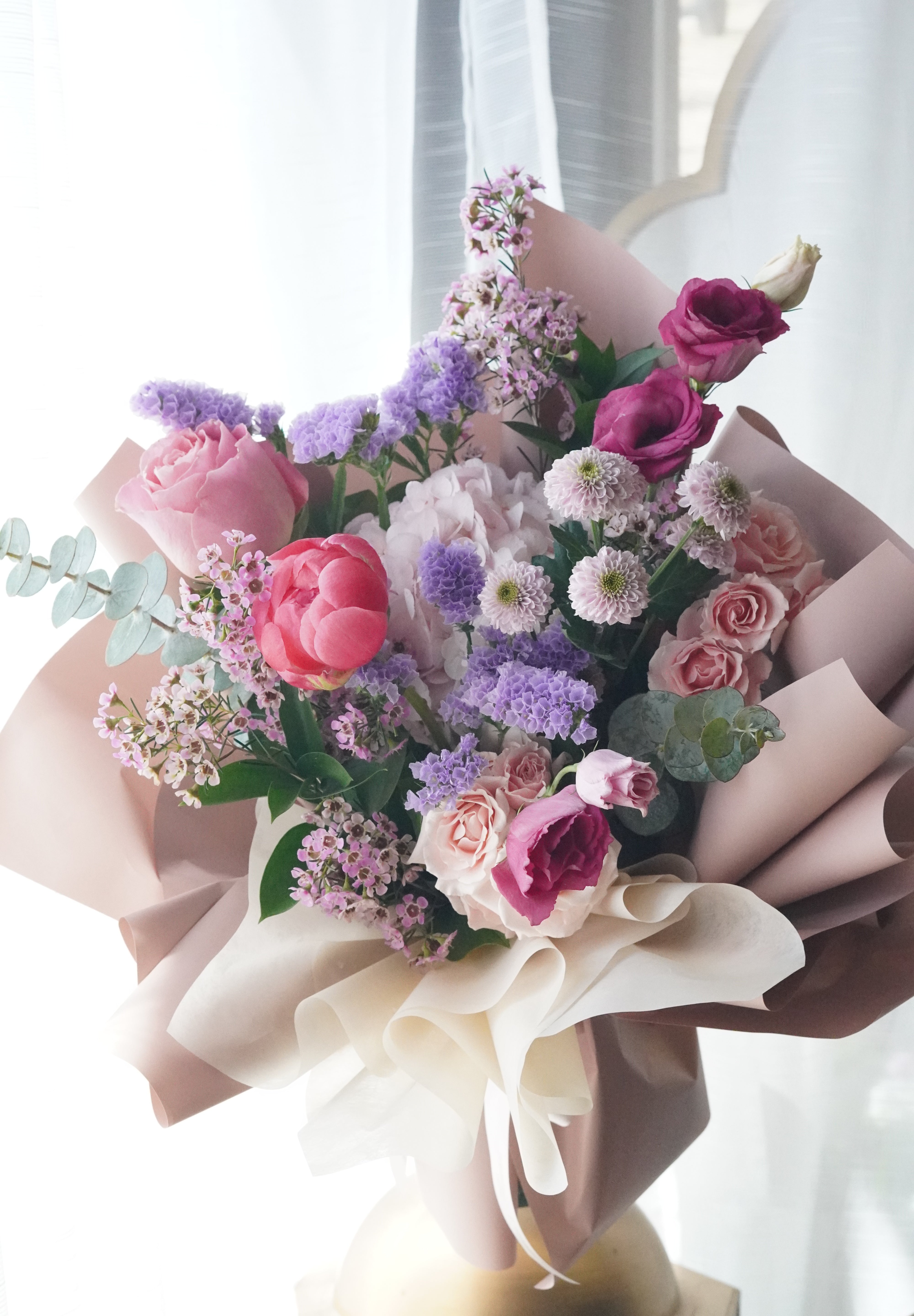 Hand-tied Mother's Day flower bouquet featuring blush pink peonies, purple roses, and lavender stock, wrapped in premium soft-toned paper for delivery in Toronto and Oakville