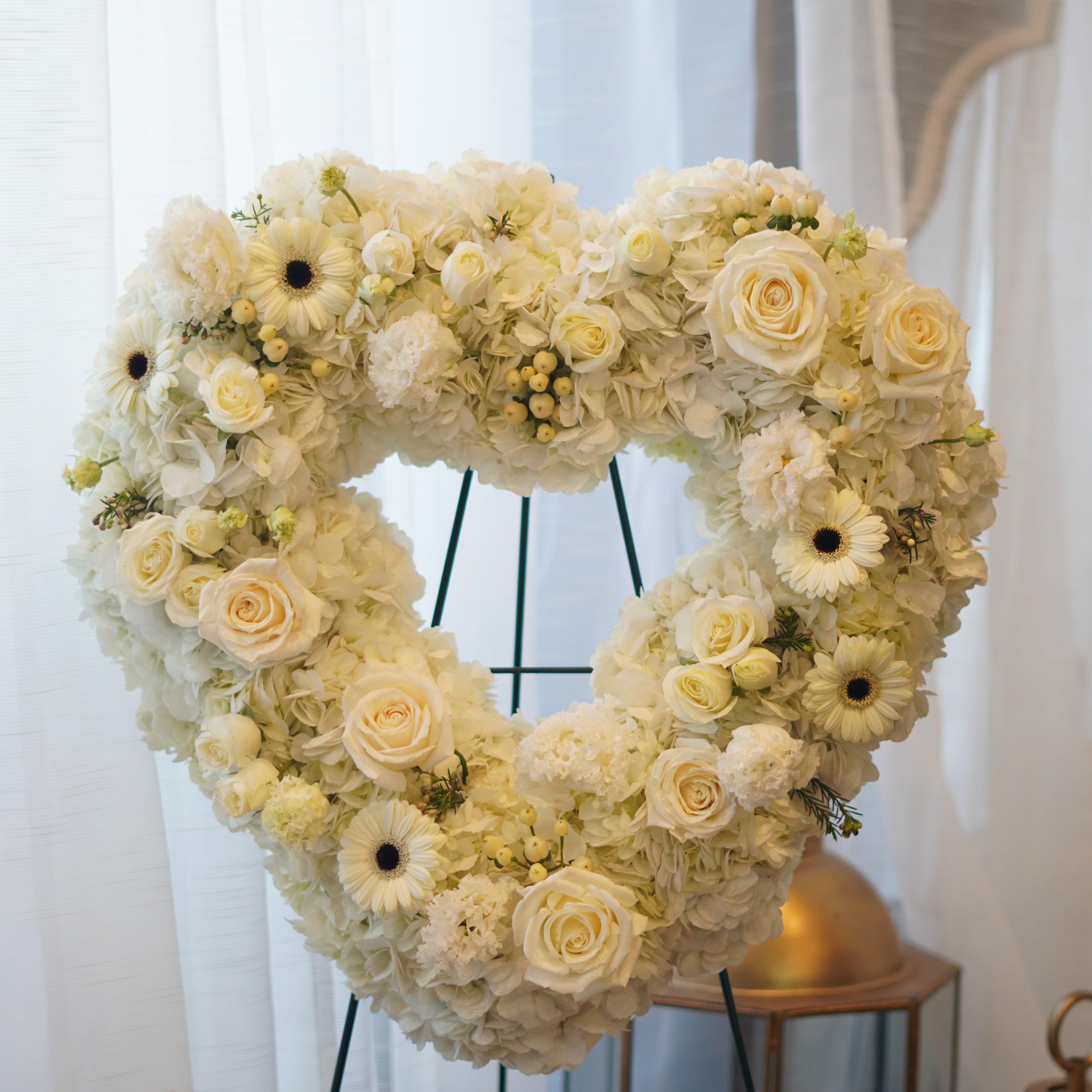 Heart-shaped funeral wreath with white roses, gerberas, and carnations for memorial services in Toronto.