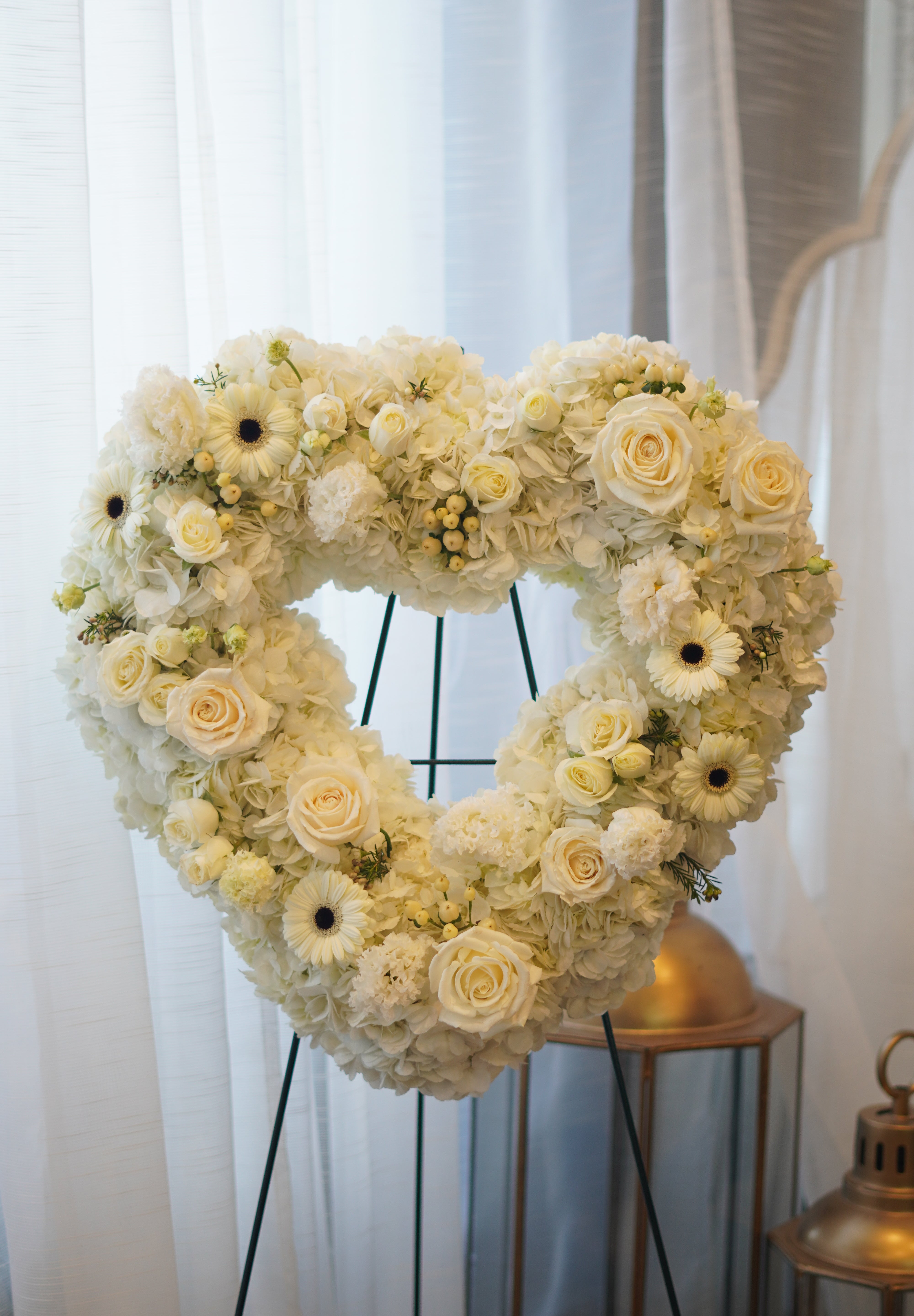 Heart-shaped funeral wreath with white roses, gerberas, and carnations for memorial services in Toronto.