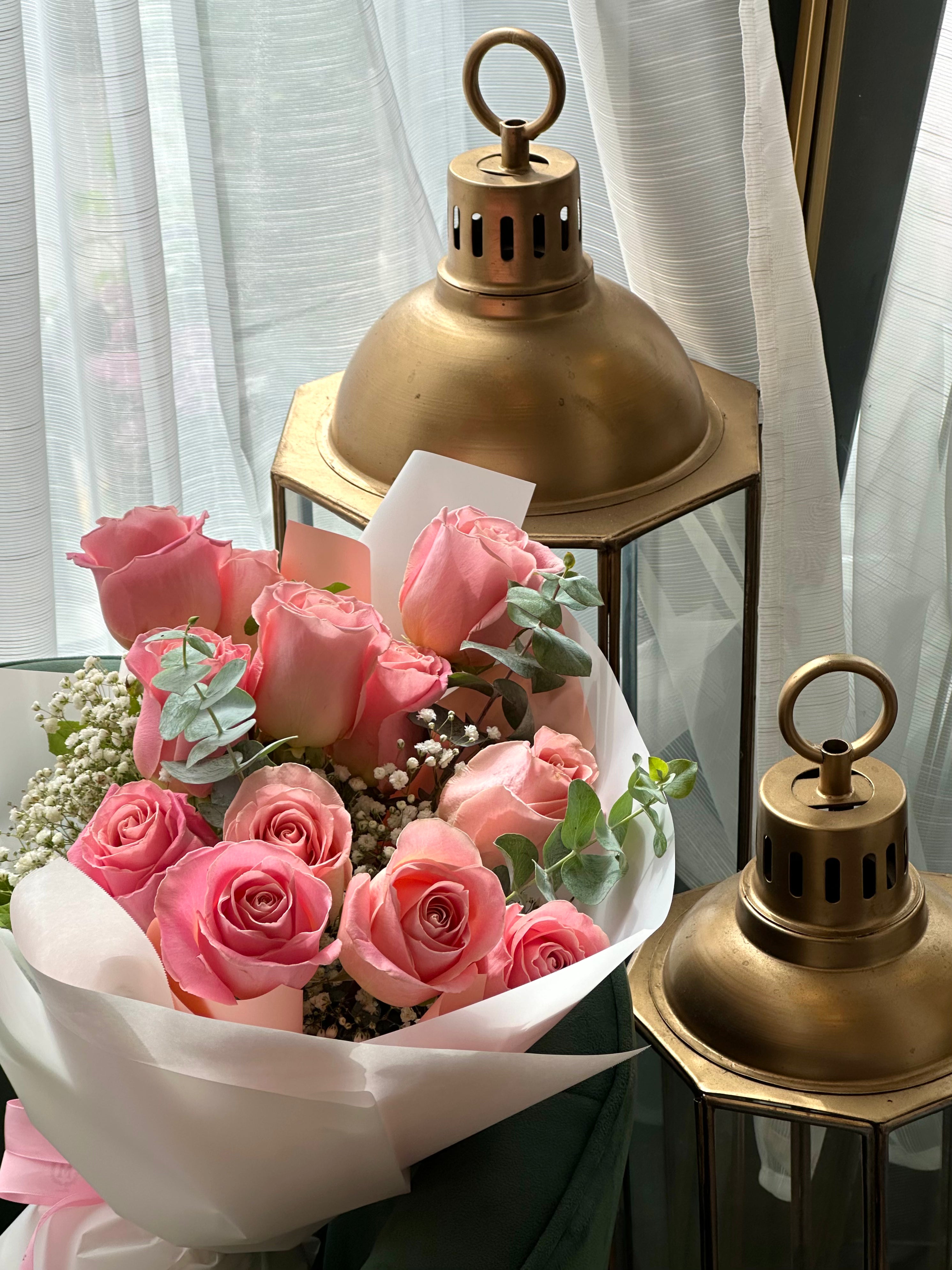 Classic pink rose dozen bouquet styled on a chair with roses and greenery