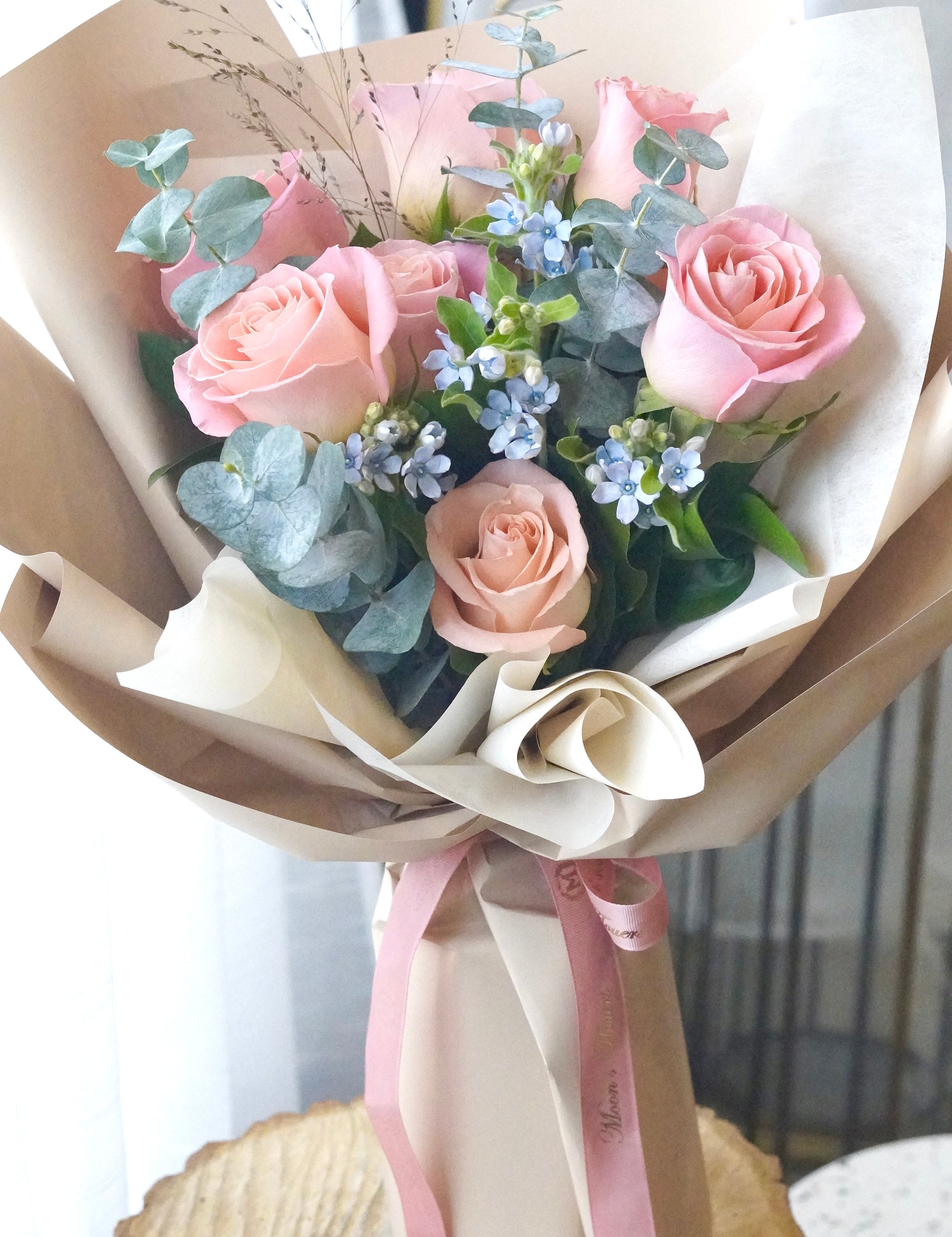 Sky blush rose bouquet featuring soft pink roses with blue accent flowers and fresh greenery