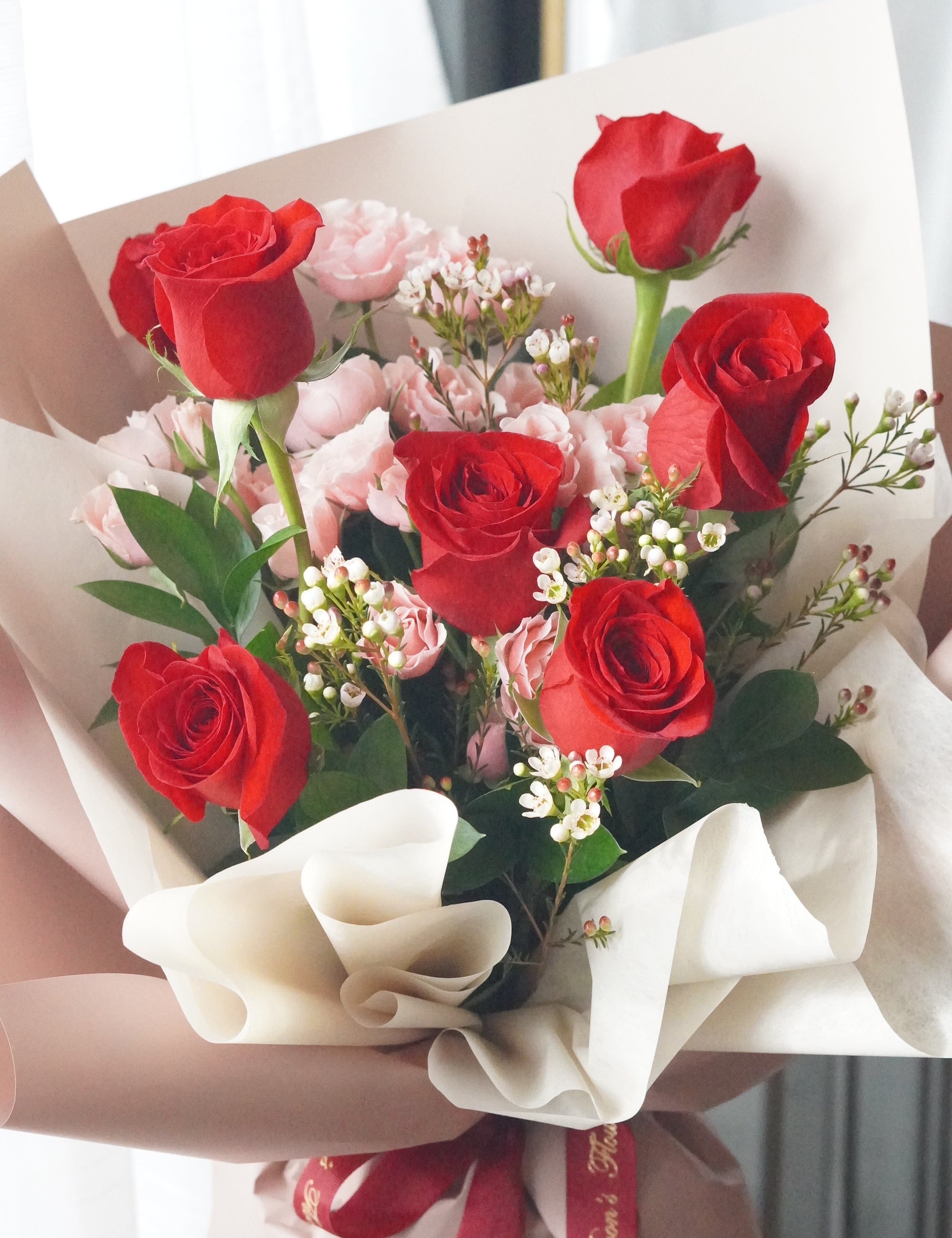 Close-up of red roses and pink spray roses with waxflower highlighting soft color contrast
