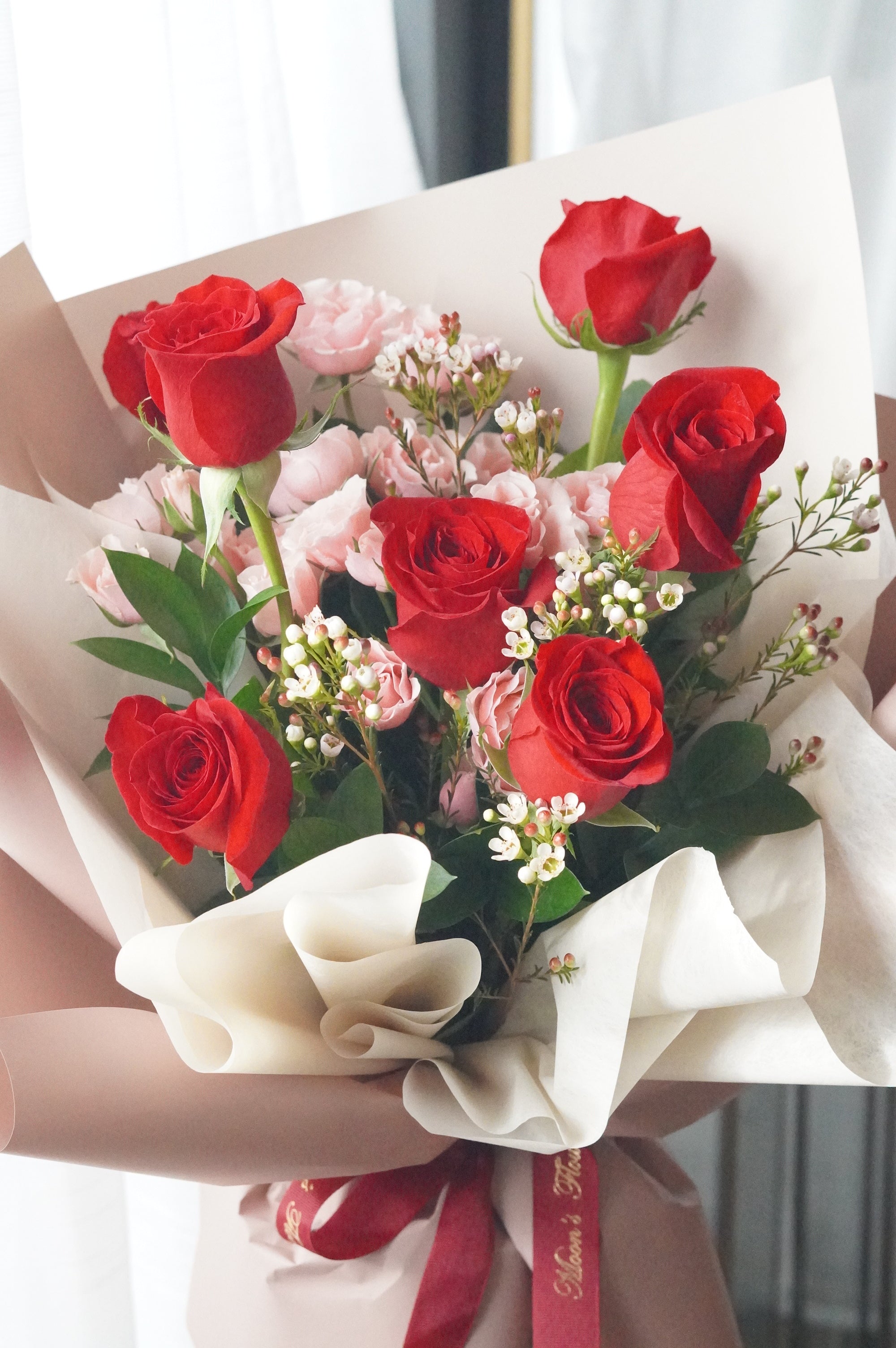 Close-up of red roses and pink spray roses with waxflower highlighting soft color contrast