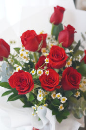 Close-up of red roses with chamomile flowers highlighting a natural garden-style arrangement