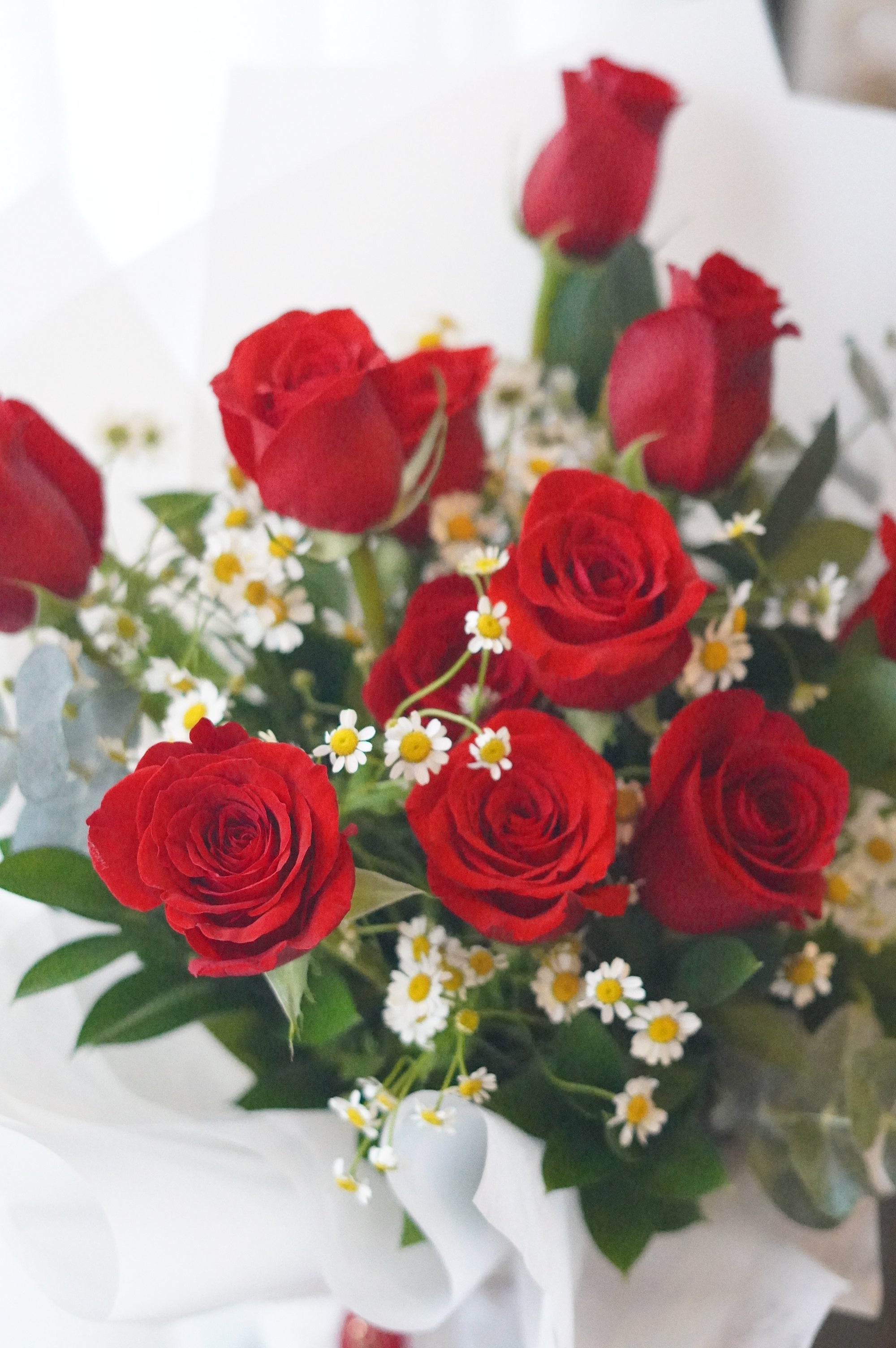 Close-up of red roses with chamomile flowers highlighting a natural garden-style arrangement