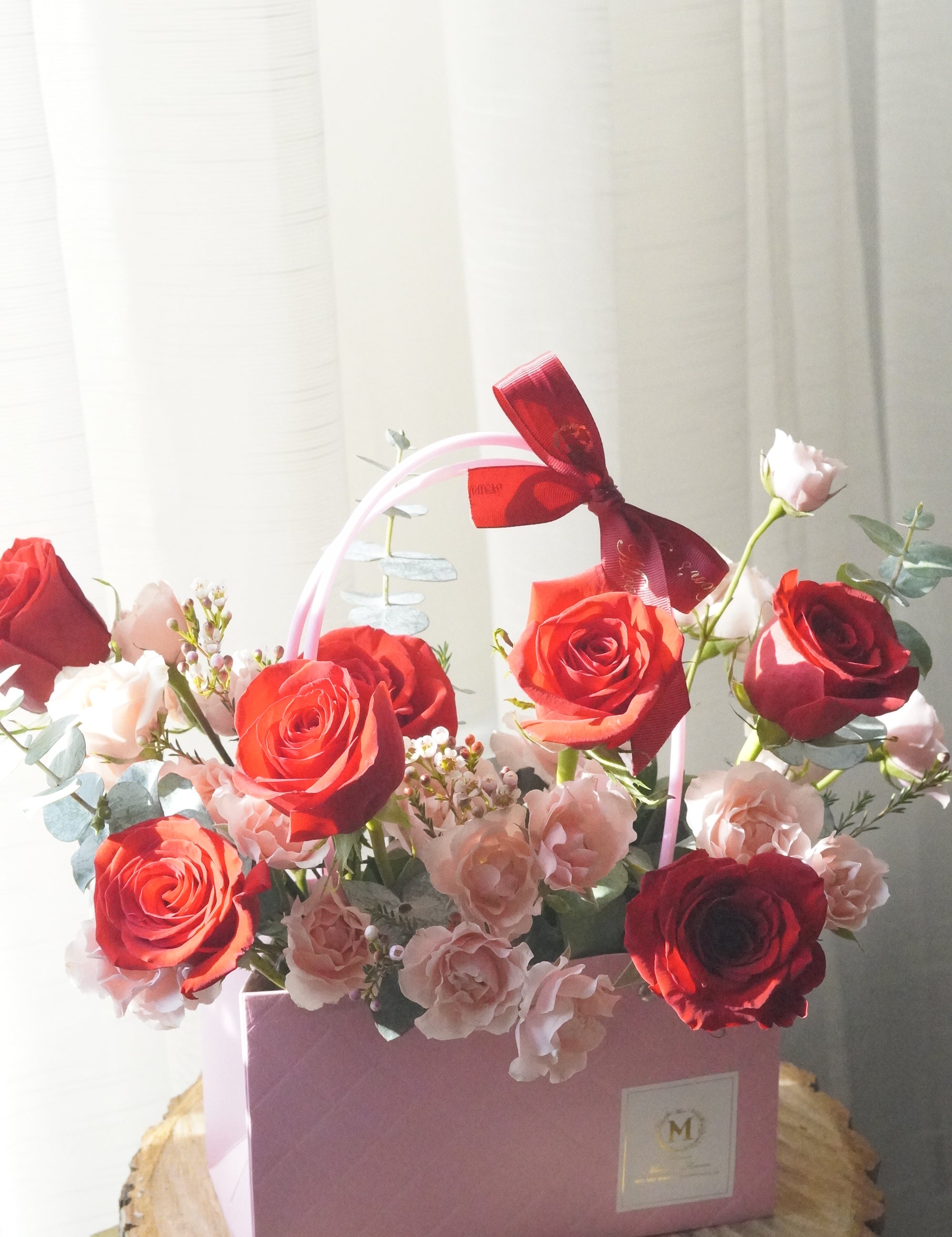 Red and blush rose basket arrangement with roses and spray roses displayed as a vase-style design