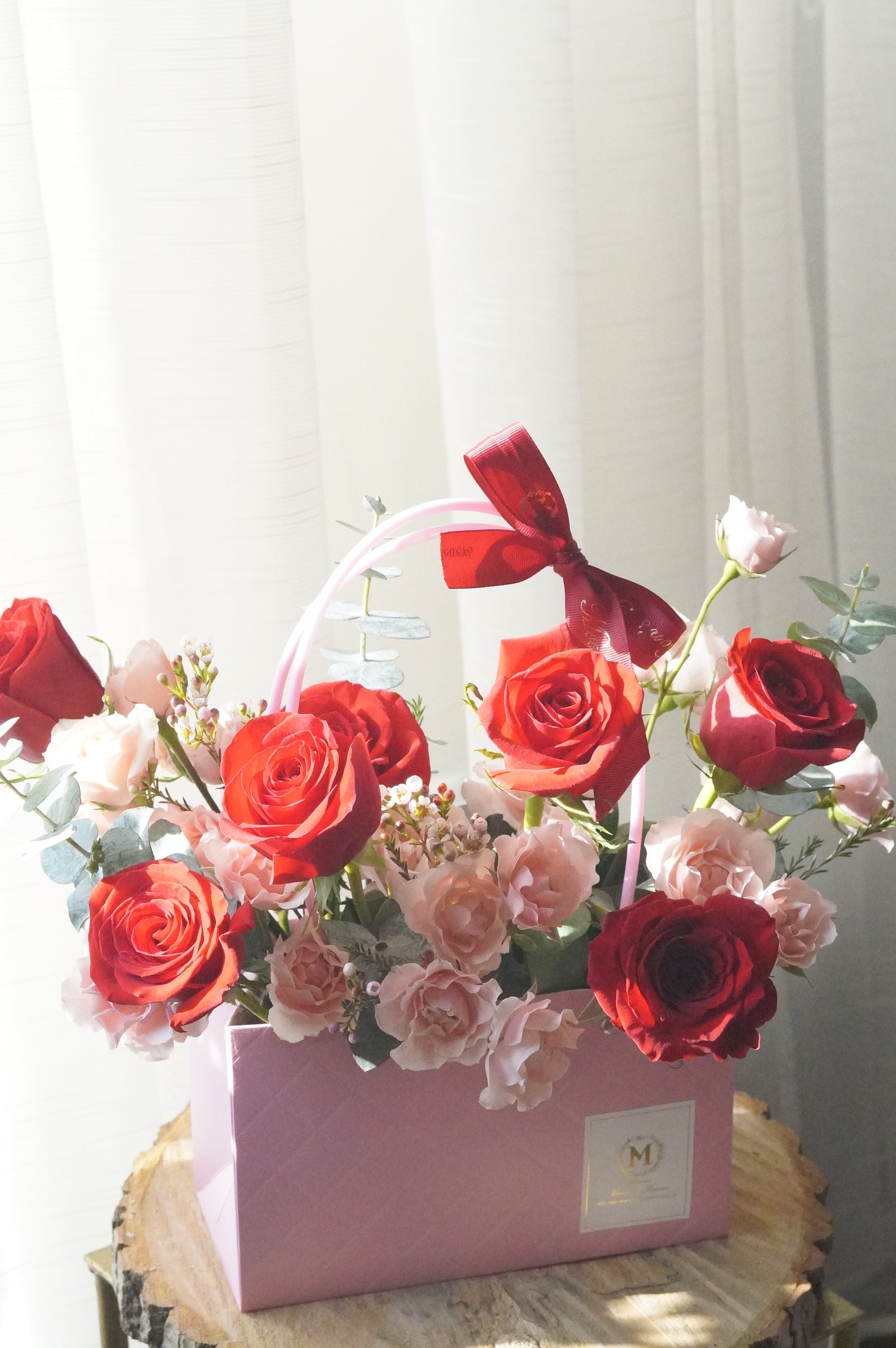 Red and blush rose basket arrangement with roses and spray roses displayed as a vase-style design