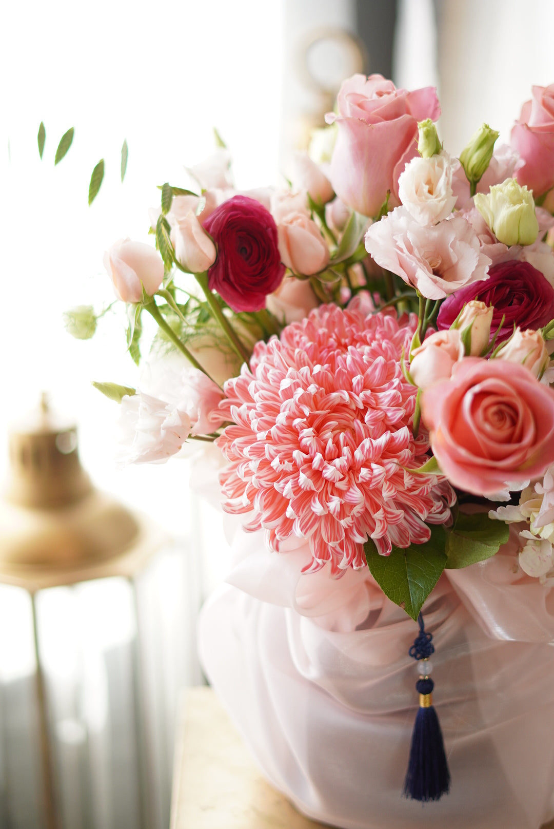 Bouquet of pink and red flowers with a decorative tassel on a white background