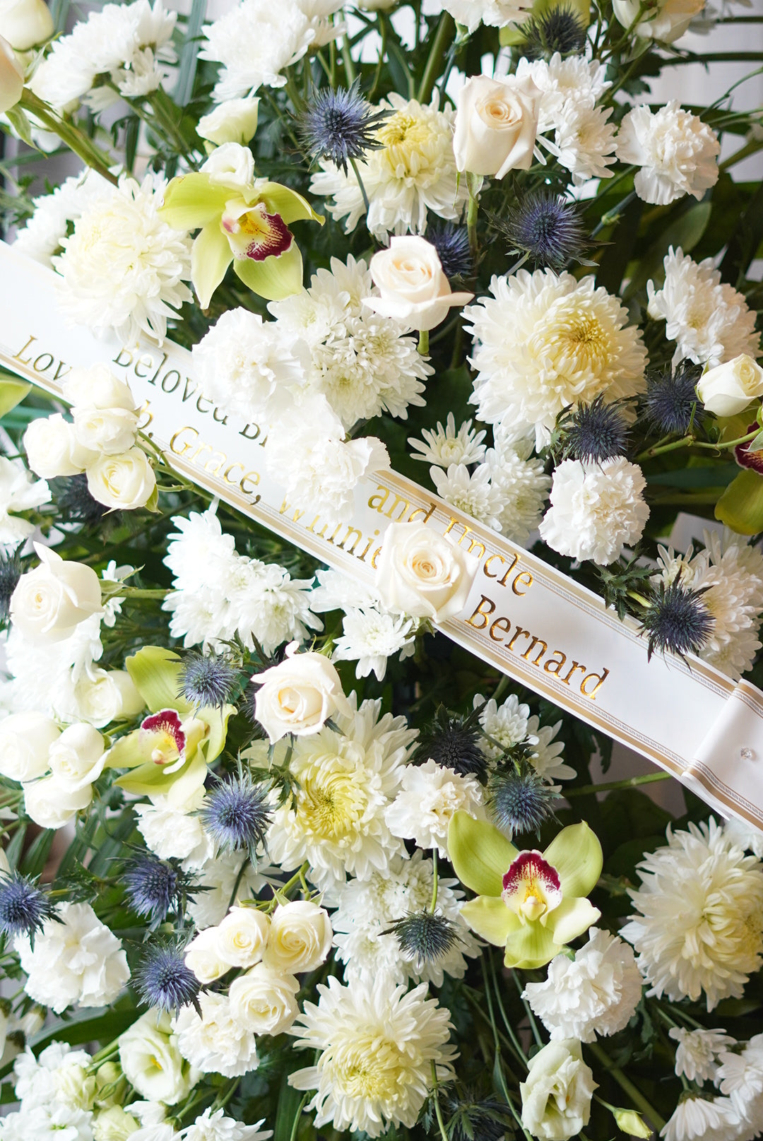 Floral arrangement with a ribbon and text on a white background, Funeral and Sympathy Flowers Delivery Toronto