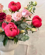Lovely Peony closeup showing the fresh seasonal flowers and foliage like eucalyptus and spray roses.