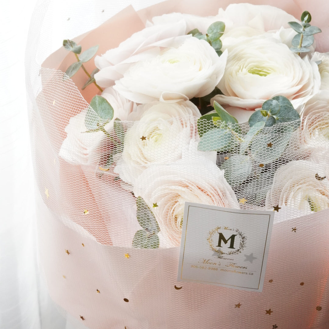 Luxury white ranunculus bouquet with star dotted pink wrapping paper. premium floral design by Moon's Flowers. Available for fast flower delivery in Oakville, Toronto, and the GTA-ideal for unique birthday or Mother's day gift 