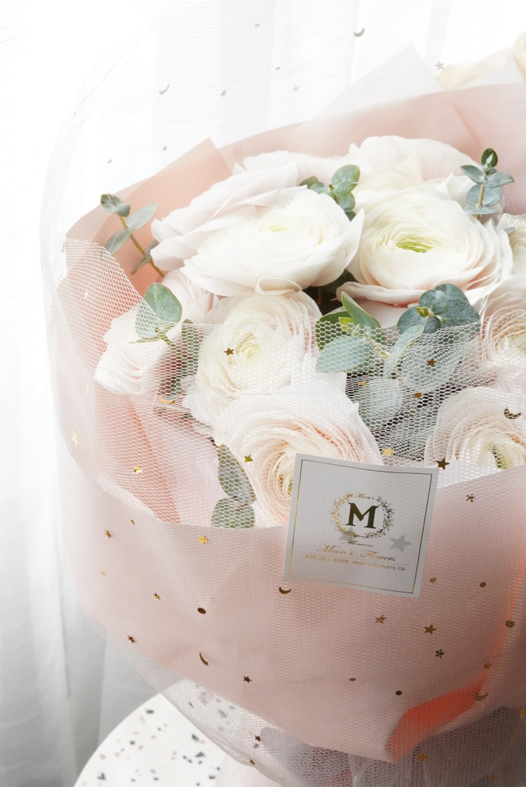 Luxury white ranunculus bouquet with star dotted pink wrapping paper. premium floral design by Moon's Flowers. Available for fast flower delivery in Oakville, Toronto, and the GTA-ideal for unique birthday or Mother's day gift 