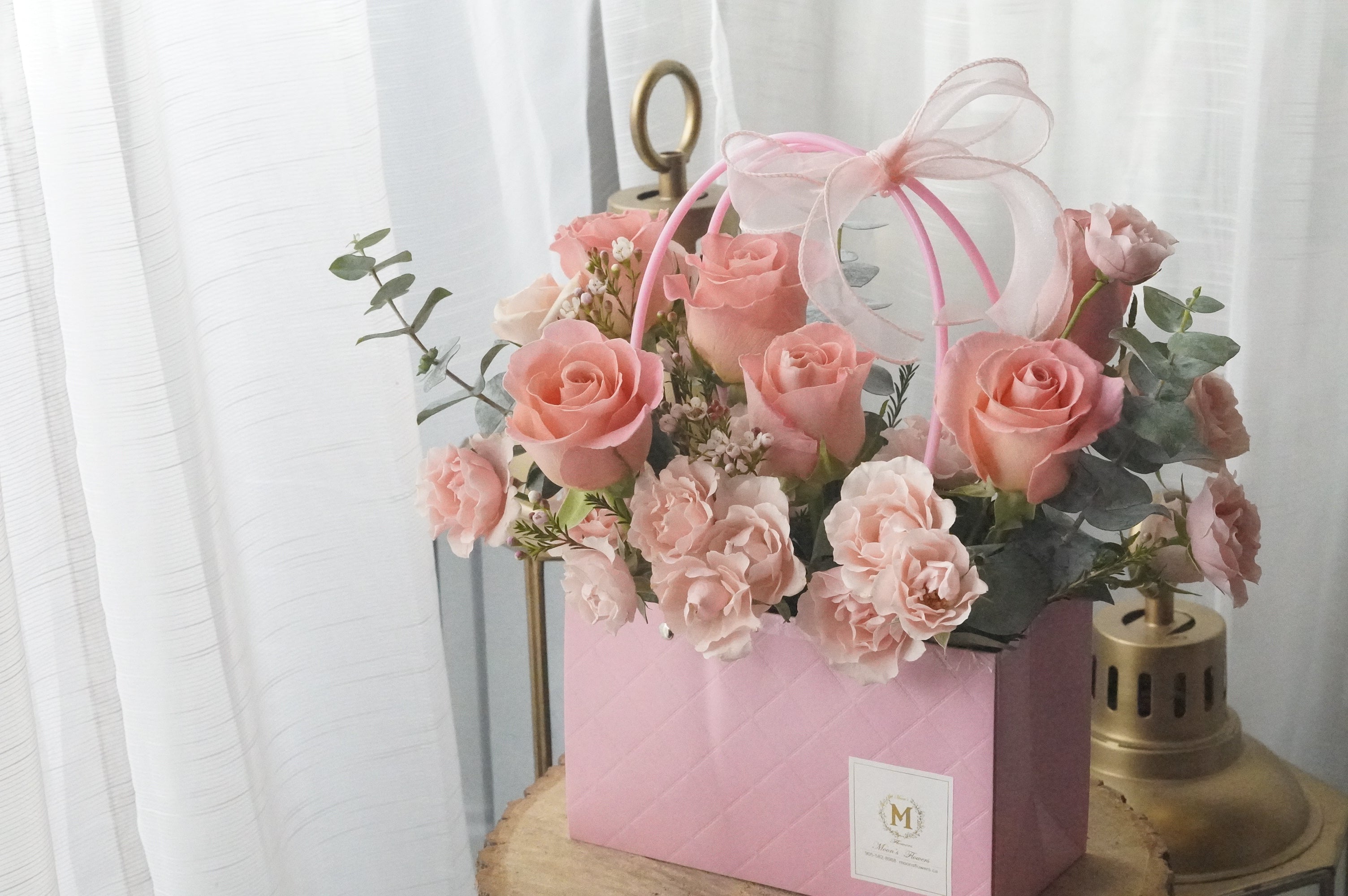 Pink and blush rose basket arrangement with roses and spray roses displayed as a vase-style design