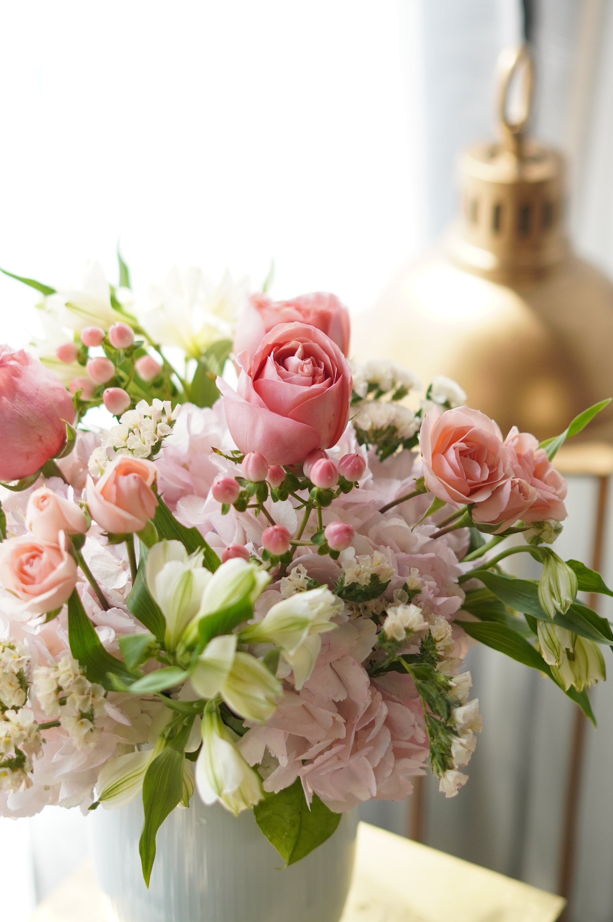 Bouquet of pink and white flowers with green leaves on a light background