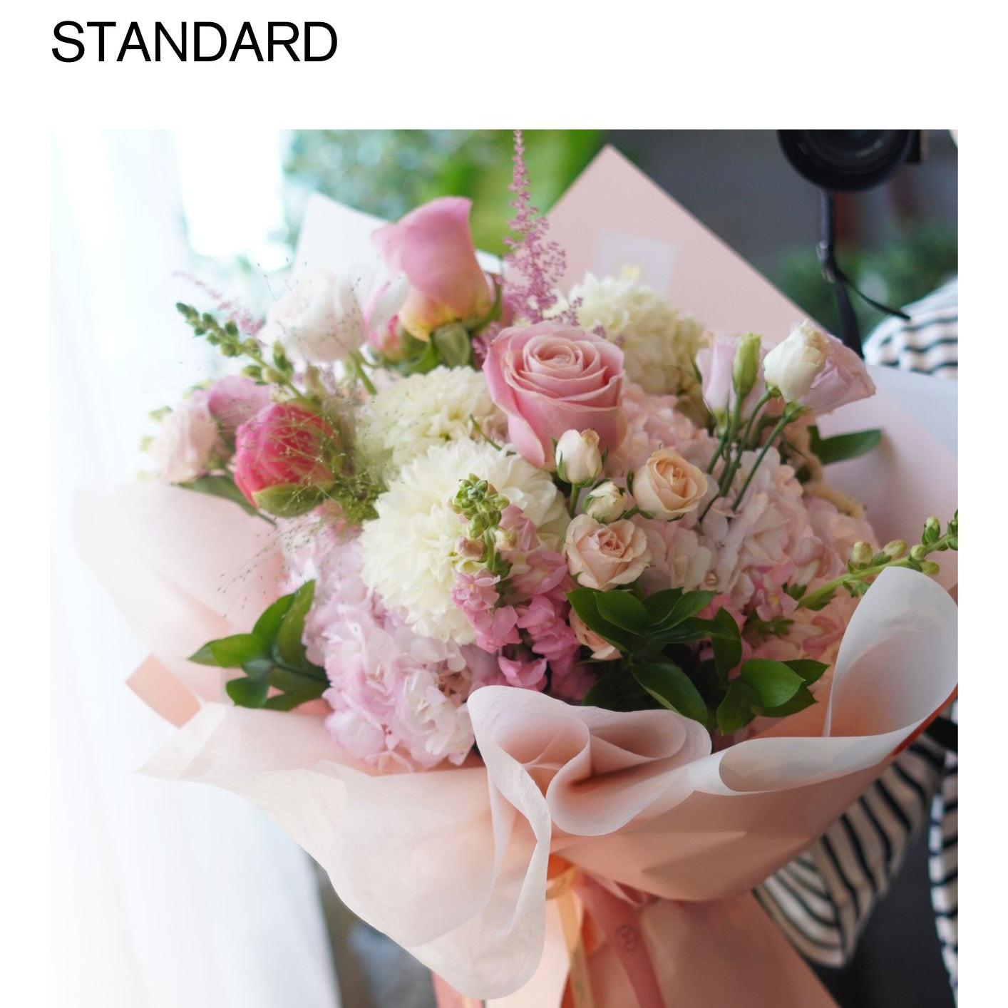 Pink Day Bouquet featuring soft pink roses, blush ranunculus, and white seasonal flowers wrapped in elegant pink decorative paper