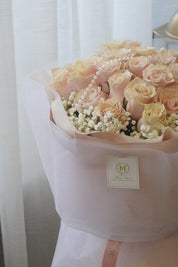 Bouquet of pink and white flowers wrapped in white paper with a Moon's Flowers brand label.