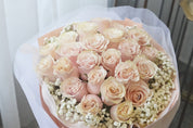 Closeup of Bouquet of pink roses with baby's breath in a white wrap.