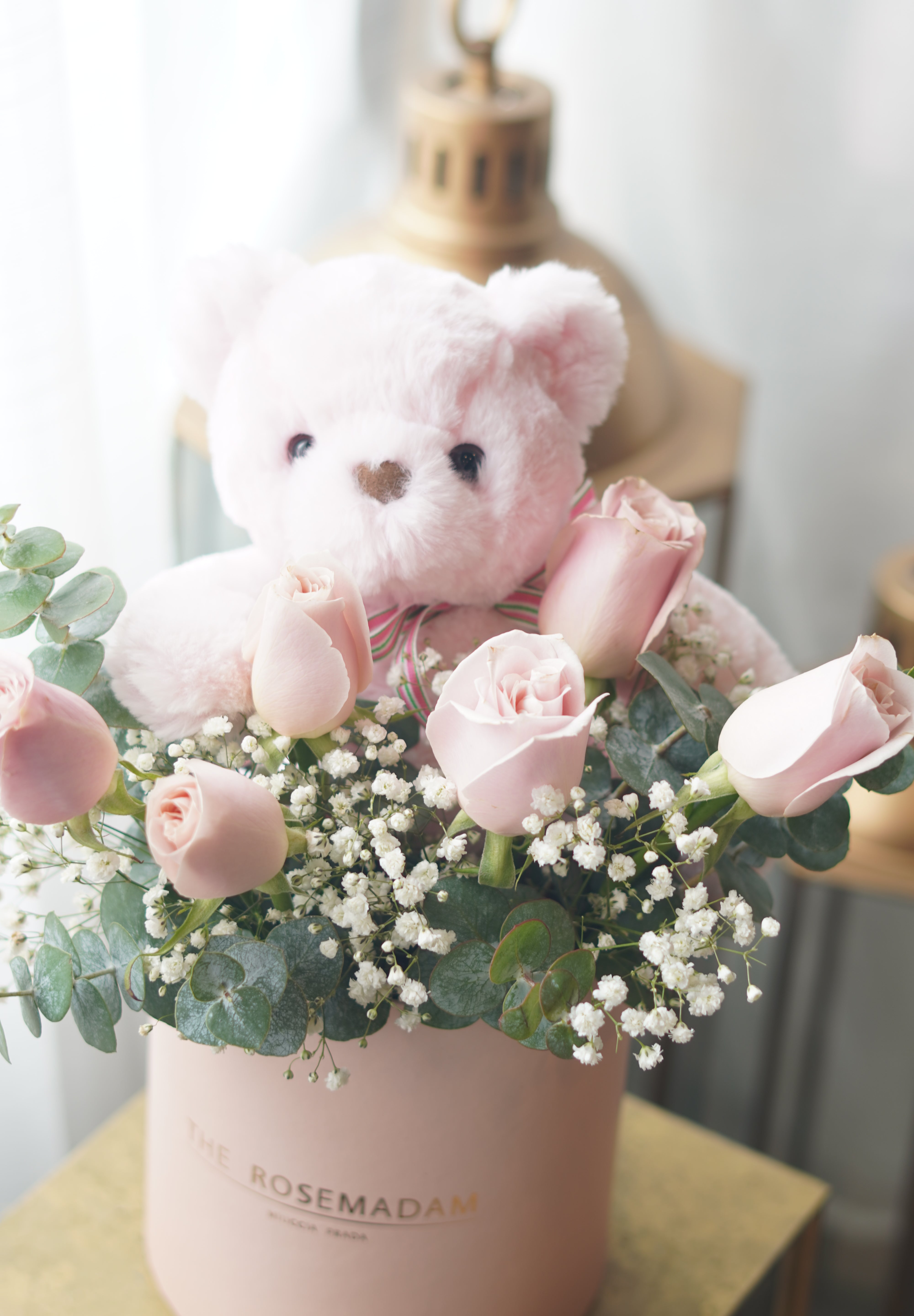 Pink rose arrangement in hat box with teddy bear and eucalyptus greenery
