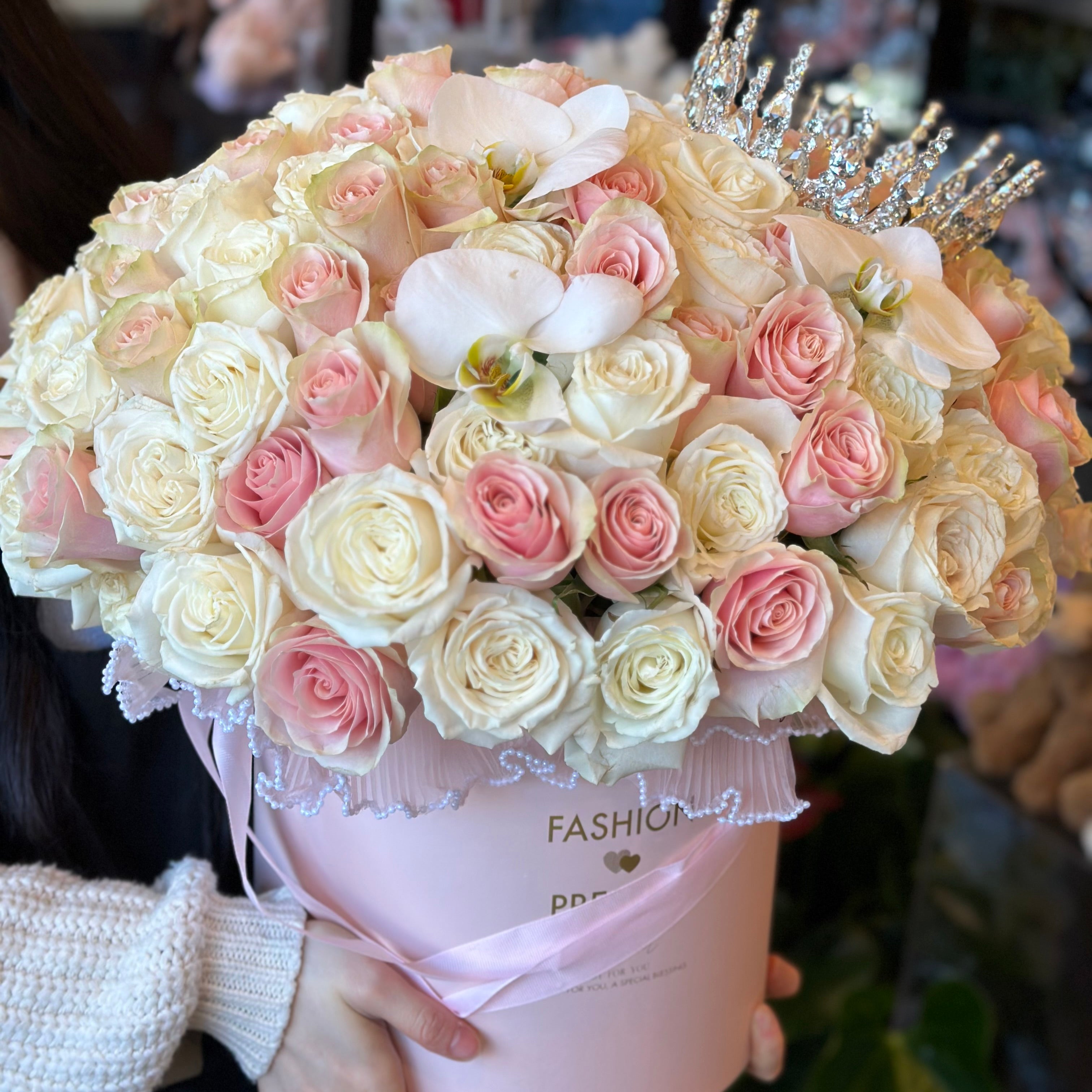 Blush pink and cream rose arrangement topped with sparkling tiara in a pink box by Moon's Flowers delivery in Toronto