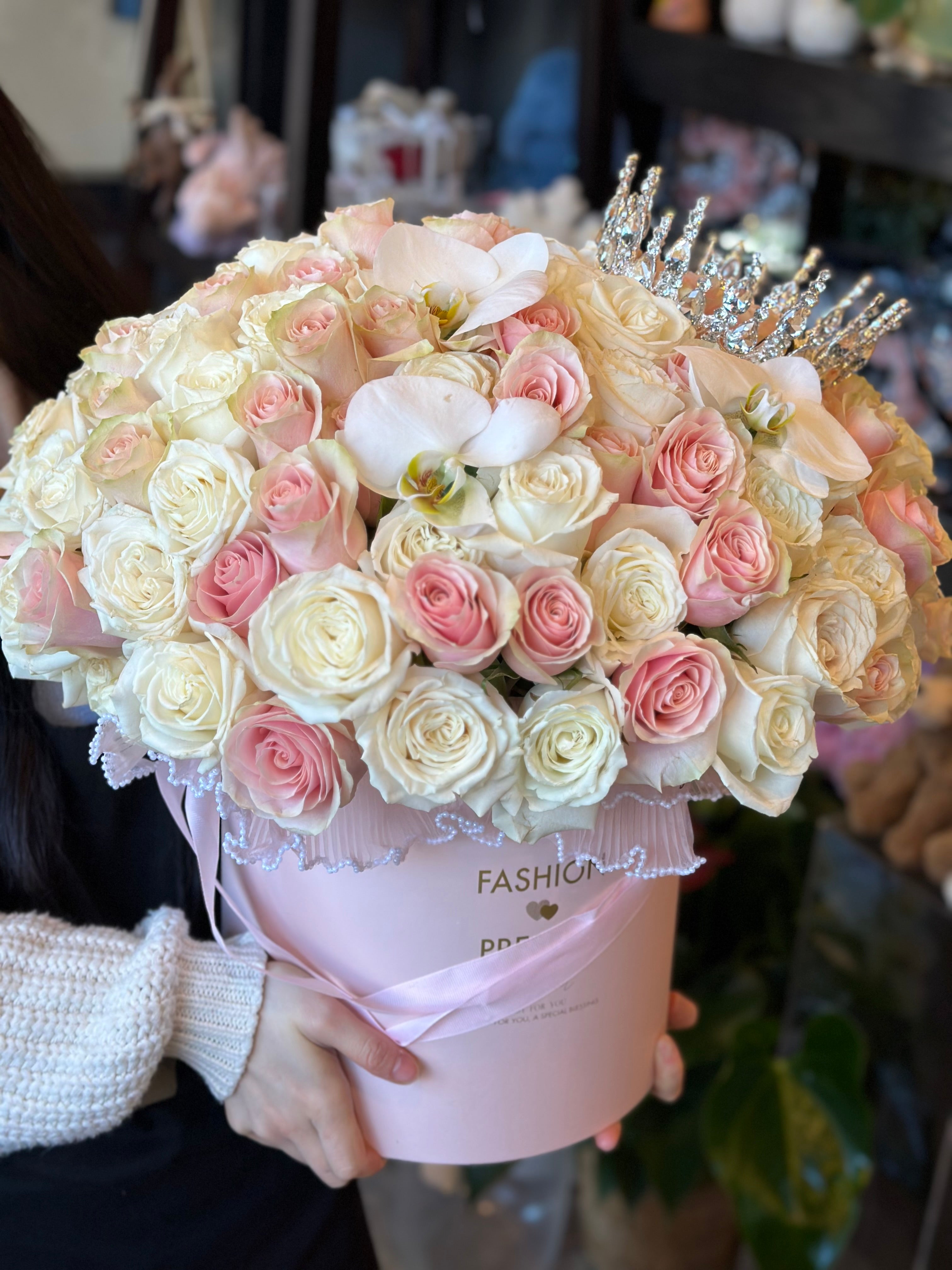 Blush pink and cream rose arrangement topped with sparkling tiara in a pink box by Moon's Flowers delivery in Toronto