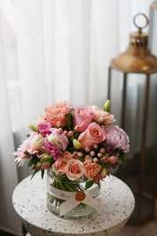 Mother's Day 'Pretty Pink' floral arrangement in a clear glass vase with pink roses and hypericum berries. Premium flower gift styled on a terrazzo side table, available for same-day delivery in Toronto by Moon's Flowers