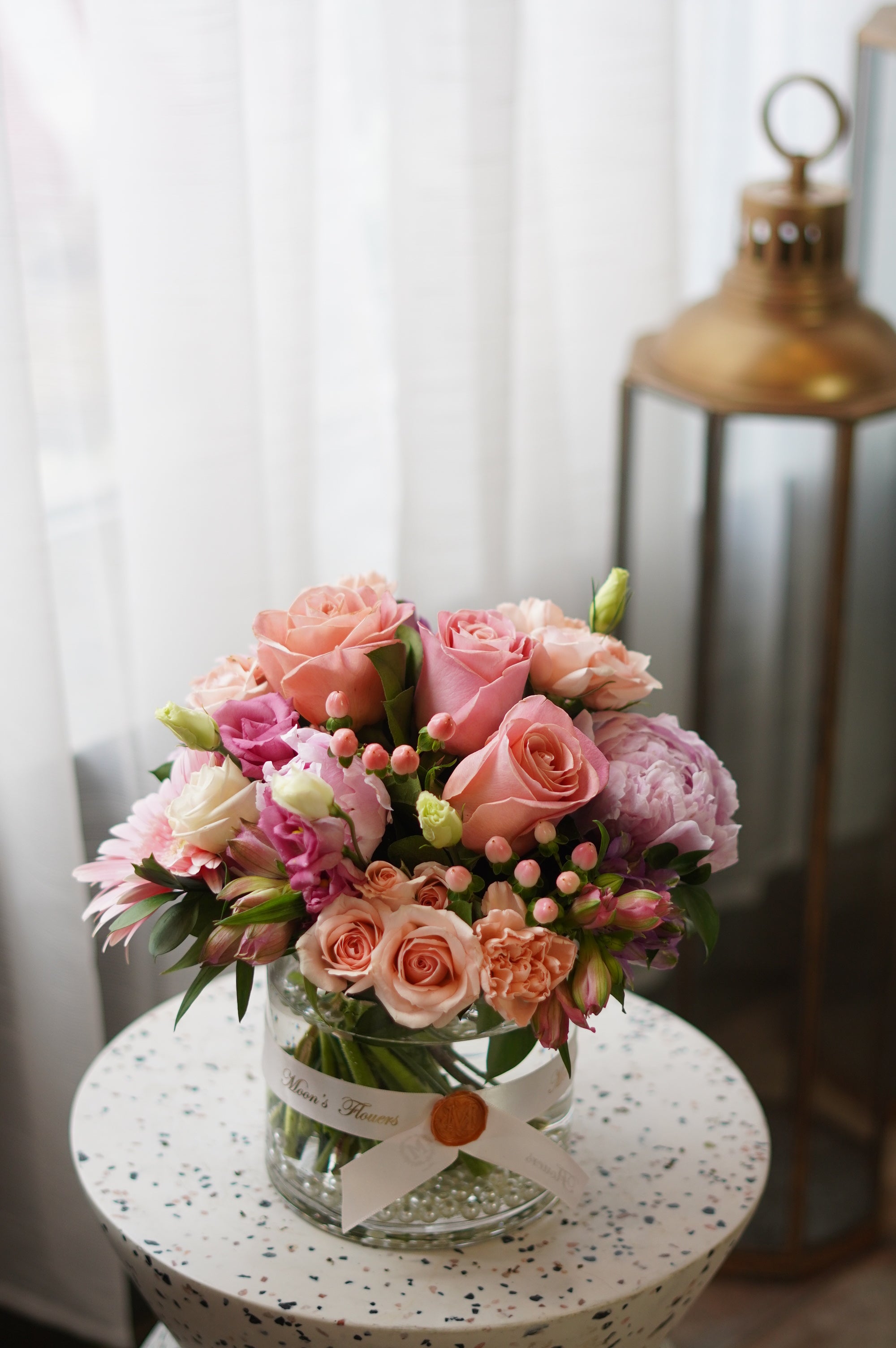 Mother's Day 'Pretty Pink' floral arrangement in a clear glass vase with pink roses and hypericum berries. Premium flower gift styled on a terrazzo side table, available for same-day delivery in Toronto by Moon's Flowers