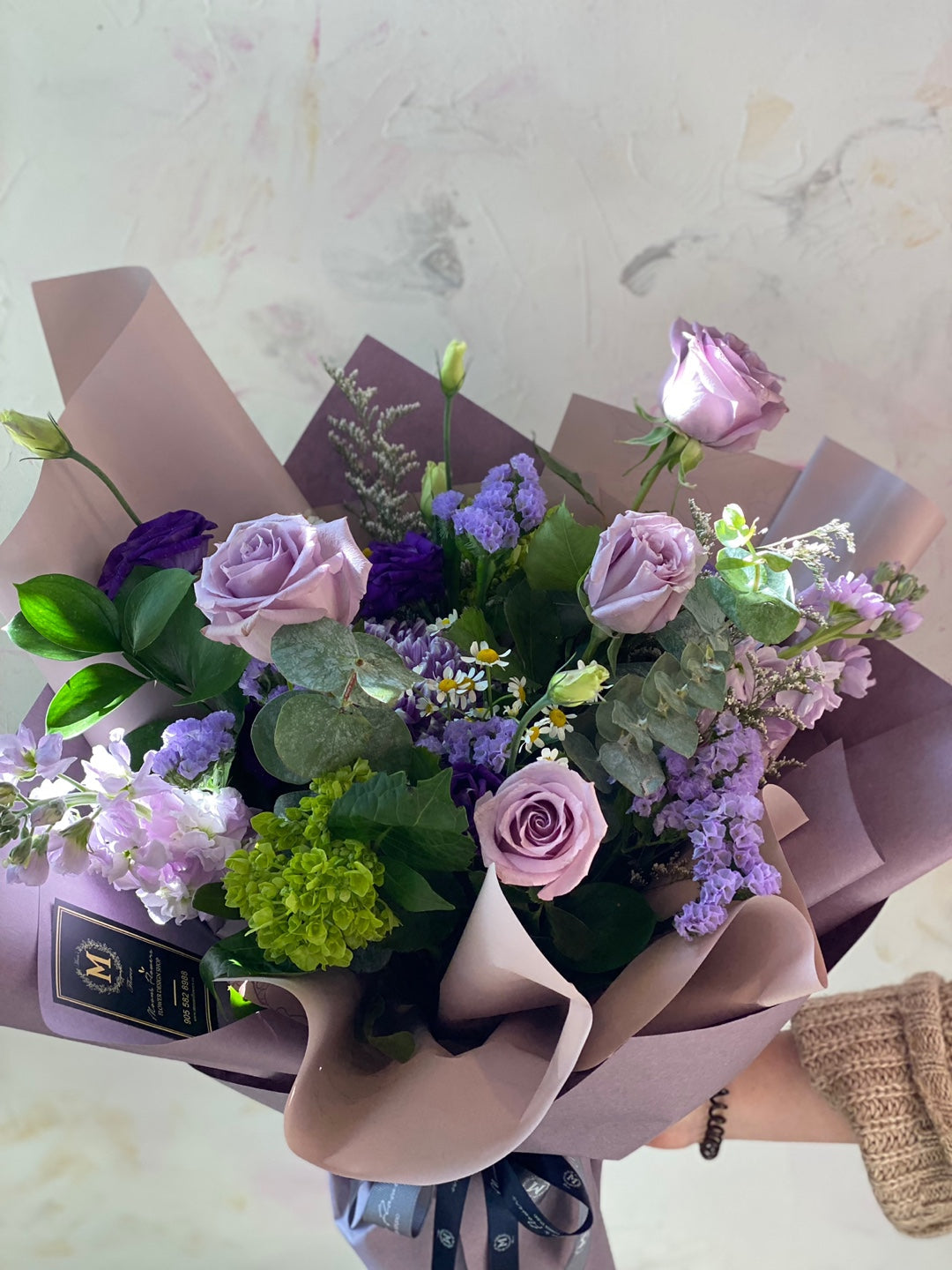 Side view of the Purple Rush bouquet featuring a mix of lavender roses, purple lisianthus, and fresh greenery in a soft mauve designer wrap. Premium Mother's Day gift from Moon's Flowers Toronto