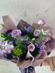 Side view of the Purple Rush bouquet featuring a mix of lavender roses, purple lisianthus, and fresh greenery in a soft mauve designer wrap. Premium Mother's Day gift from Moon's Flowers Toronto
