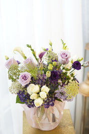 Purple and lavender Mother's Day floral arrangement featuring premium roses, dark purple lisianthus, and white calla lilies in a fabric-wrapped vase with a traditional Korean tassel. Professional flower delivery in Toronto and Oakville.