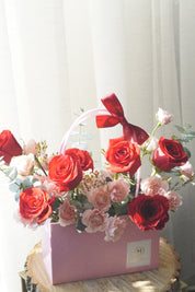 Red and blush rose basket arrangement with roses and spray roses displayed as a vase-style design