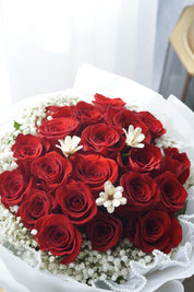 Close-up of red roses tightly arranged in a full round bouquet with white werrping